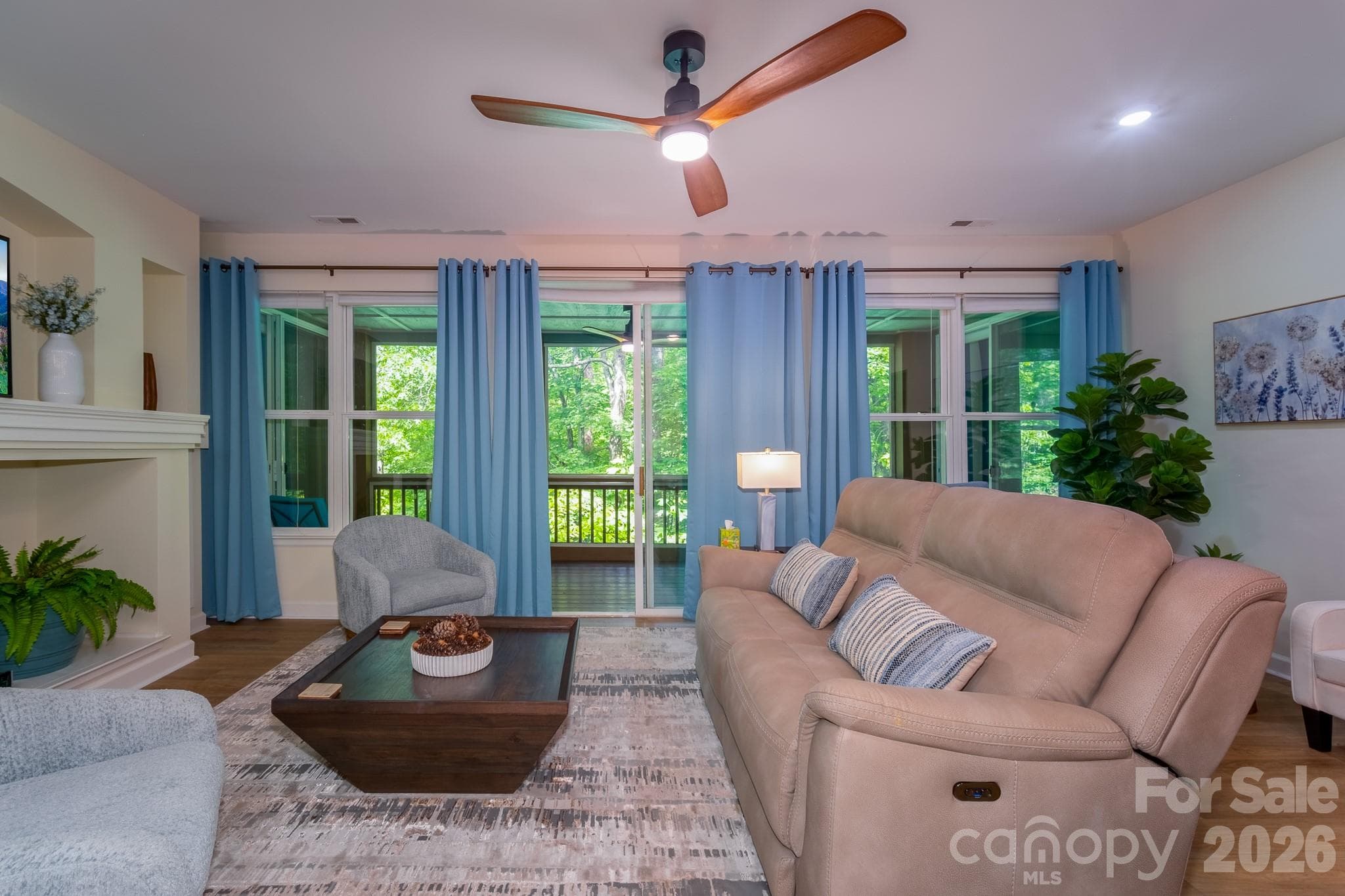 Living Room with Indoor-Outdoor Connection – Comfortable living area featuring large windows, natural light, and seamless access to the screened porch with wooded views beyond. - 99 Ridgetop Circle, Brevard