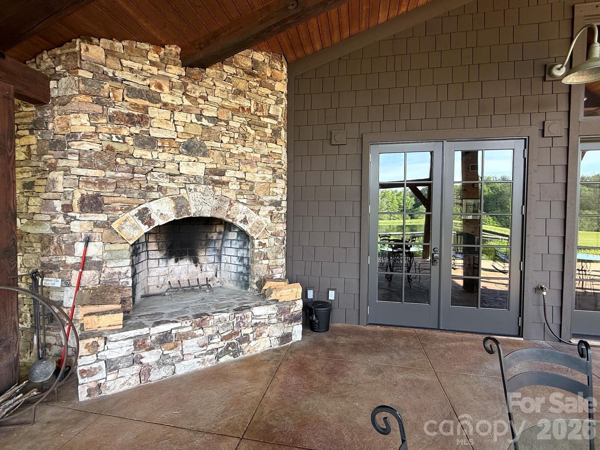 Outdoor Fireplace & Covered Gathering Space – Relax year-round beside the impressive floor-to-ceiling native stone outdoor fireplace, framed by timber beams and seamless access to covered lakeside seating. - 99 Ridgetop Circle, Brevard