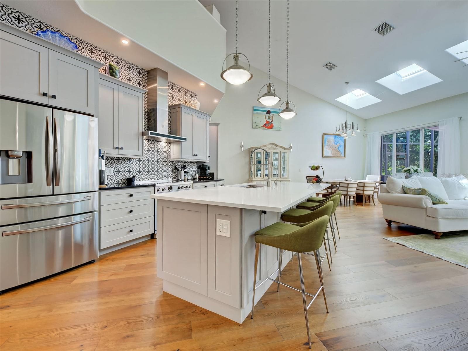 Clean lines, unique backsplash, understated counter tops and stainless-steel appliances create a welcoming kitchen space. - 5026 HANGING MOSS LN, SARASOTA
