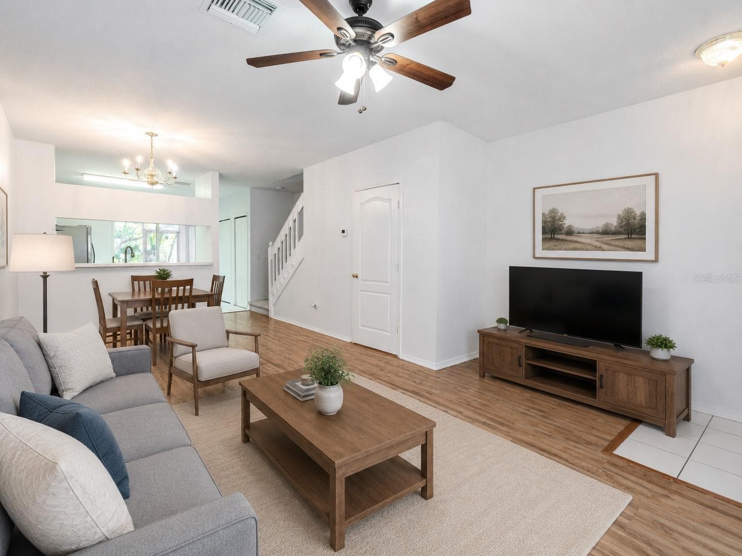 The Living room features neutral tones, wood laminate flooring, a ceiling fan with light kit and picture window. - 2432 LAKE WOODBERRY CIR, BRANDON
