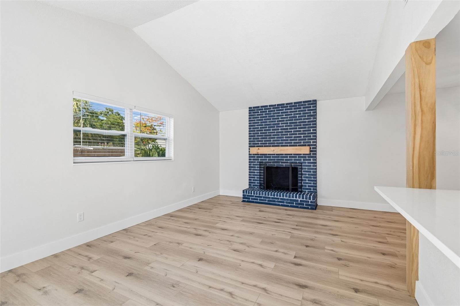 Living room with vaulted ceilings and brick wood burning fireplace. - 1101 54TH AVE S, ST PETERSBURG