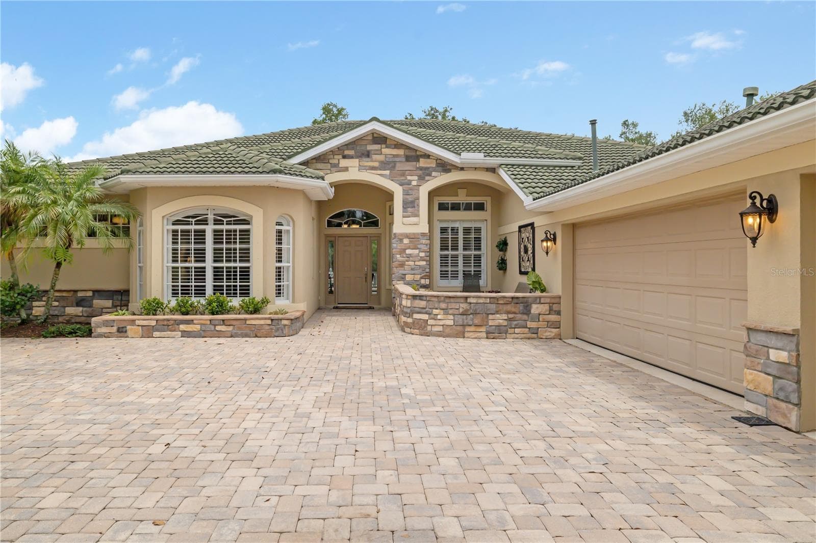 Gorgeous tile barrel roof, exterior stone veneer, paver driveway, side facing 3 car extra deep garage with epoxy flooring, hurricane rated new garage door, front porch covered sitting area perfect for morning coffee while enjoying the front Southern exposure - 12471 NATUREVIEW CIR, BRADENTON