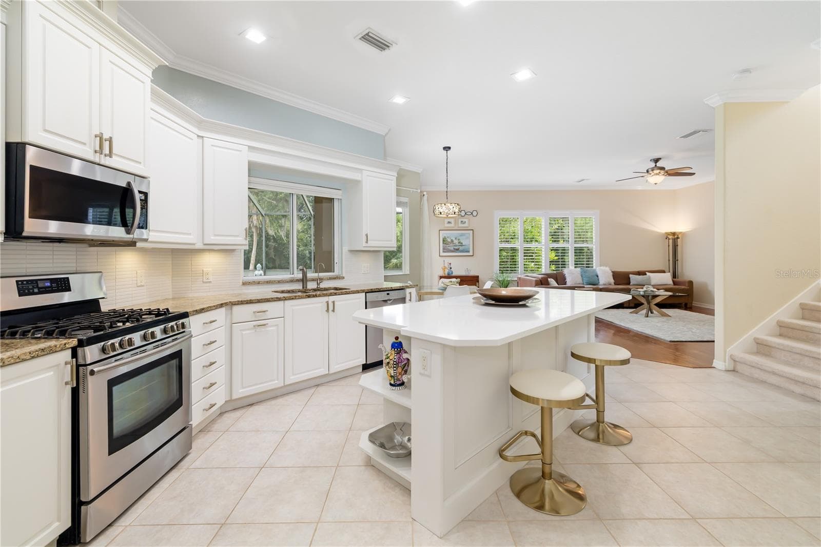 Updated modern kitchen, gas stovetop, quartz breakfast bar and stone counters, pass through window opening to the pool lanai for easy entertaining, and gathering with friends and guests year round, stairwell leading up the the 5th bedroom, and bathroom 3, bonus guest quarters - 12471 NATUREVIEW CIR, BRADENTON