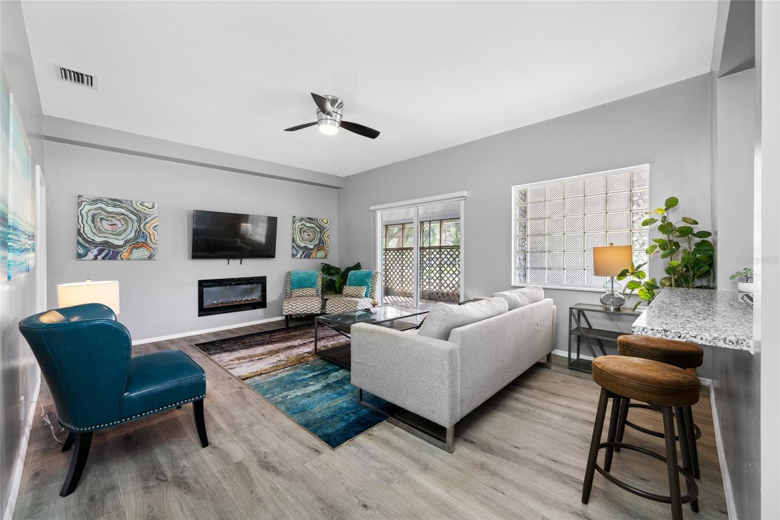 Living Room with electric fireplace and sliding door to the front screened porch - 5044 BETTY ST N, ST PETERSBURG