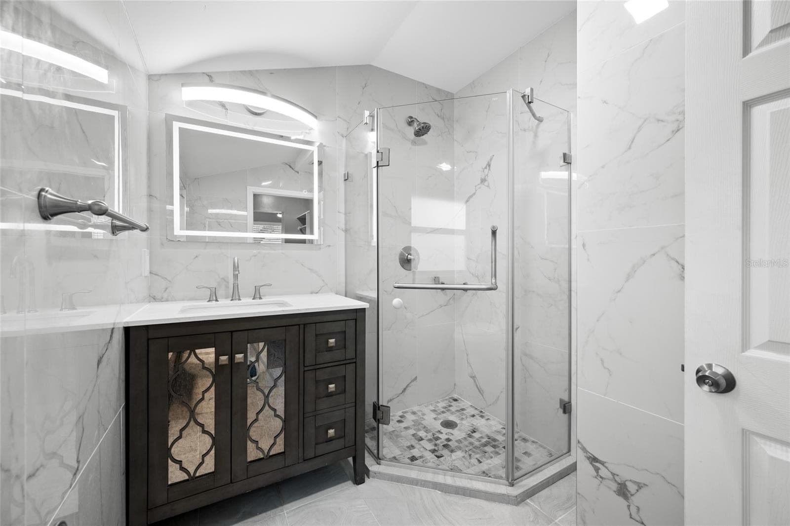 Primary Bedroom suite with walk-in closet, with built in shevles, that opens through to private en-suite updated bathroom with marble tile and glass shower. - 5044 BETTY ST N, ST PETERSBURG