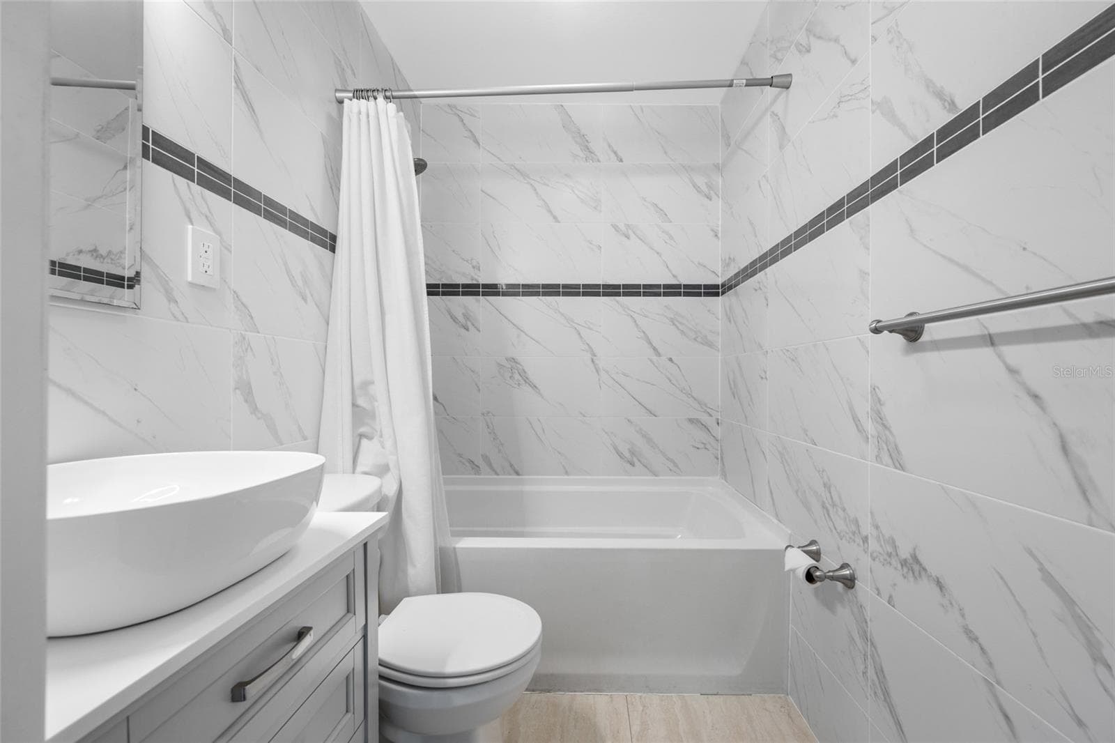 Bathroom 2 features an upgraded vanity, marble tiles, and a bathtub with shower. - 5044 BETTY ST N, ST PETERSBURG