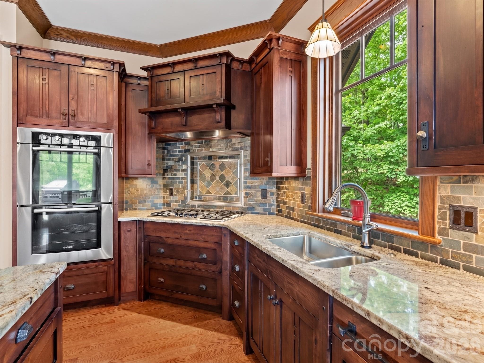 Kitchen with custom cabinetry, ss appliances, gas cook top, wall ovens stone countertops and hardwood flooring. - Hendersonville