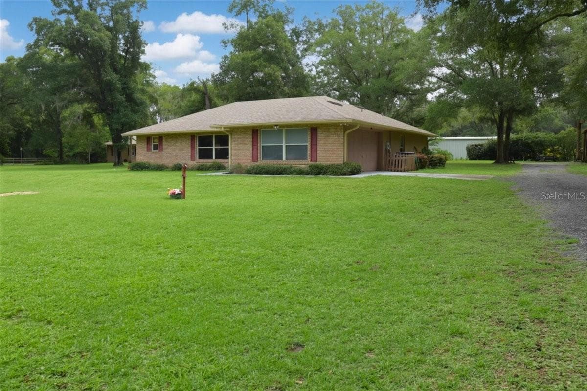 Full front elevation of this ranch-style brick home on acreage and long driveway. - 267 N ORANGE AVE, LAKE HELEN
