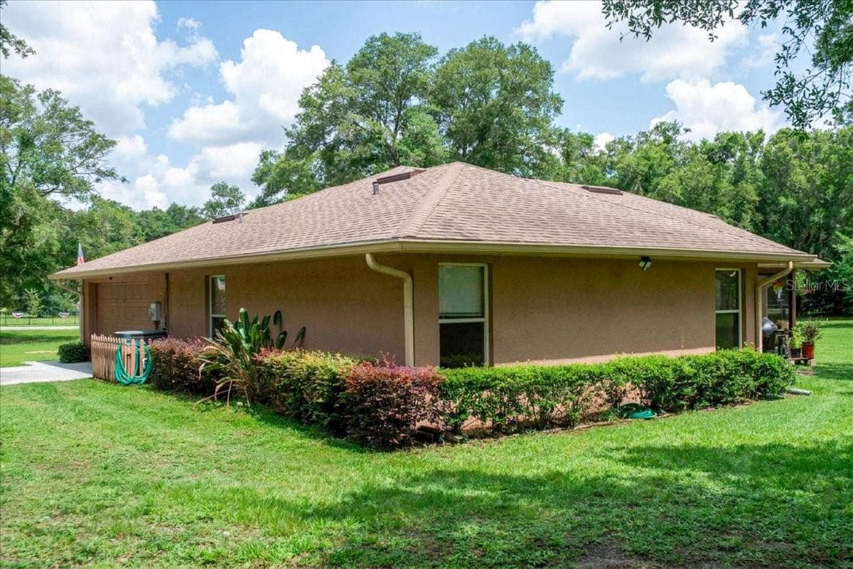Side exterior view featuring mature landscaping and shaded outdoor areas. - 267 N ORANGE AVE, LAKE HELEN