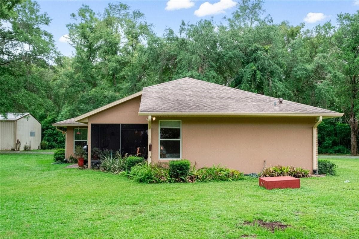 Side exterior elevation with covered patio and mature landscaping. - 267 N ORANGE AVE, LAKE HELEN
