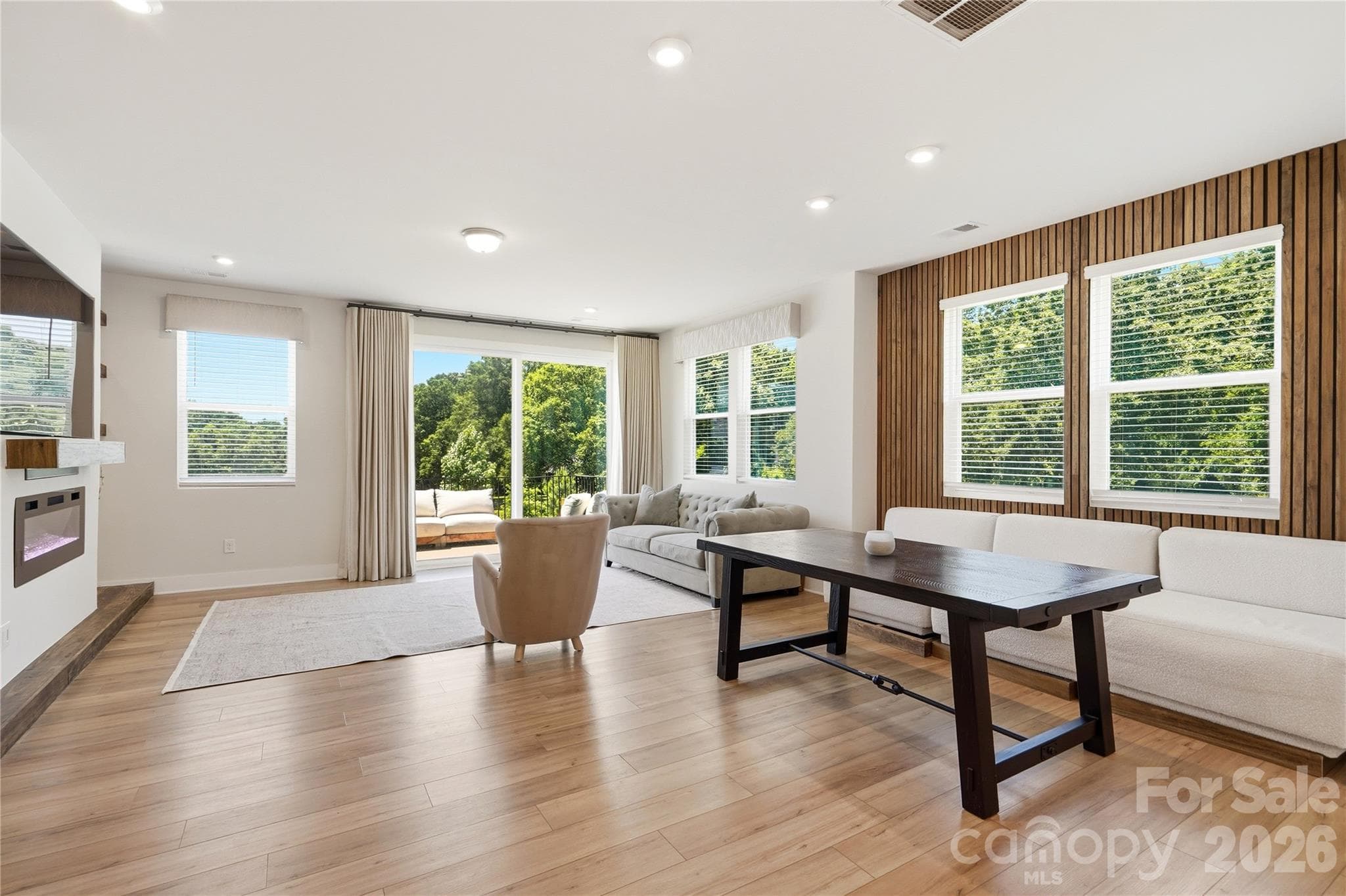 Beautifully lit living room and dining area with custom wood paneling and fire place wall unit perfect for entertaining and sure to impress your favorite guests! - 3324 Treble Court, Charlotte