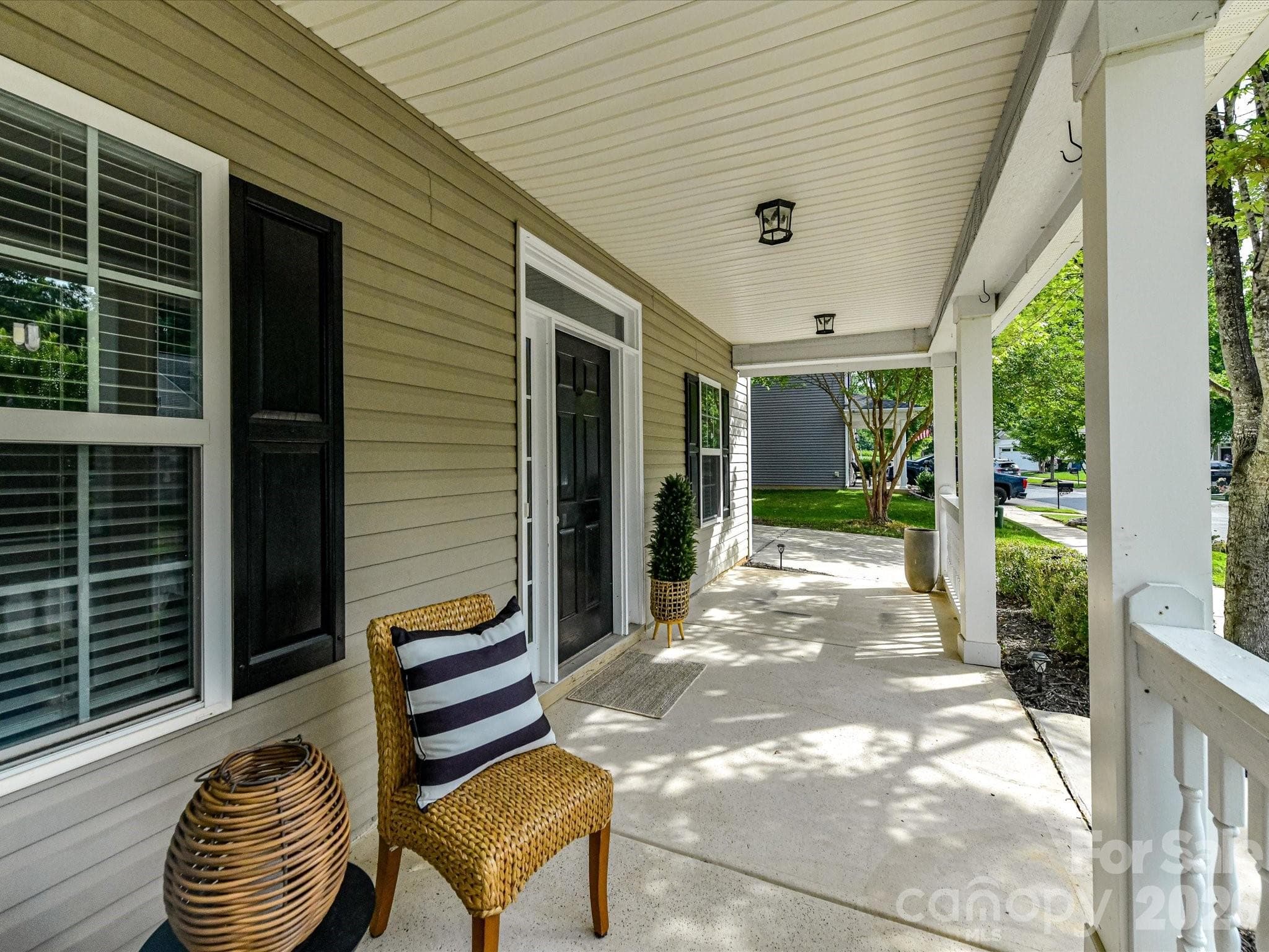 Expansive covered front porch provides a welcoming outdoor living space, perfect for relaxing and enjoying the neighborhood surroundings. - Cornelius