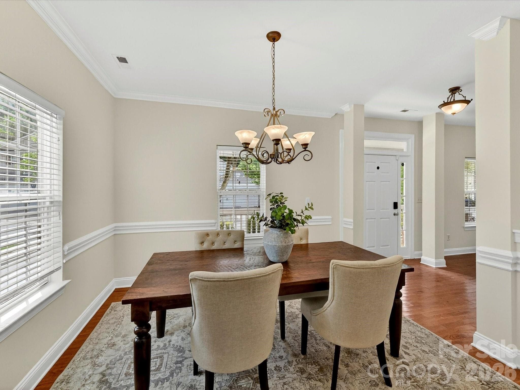 Elegant formal dining room features wood flooring, crown molding, chair rail detailing, and abundant natural light, creating the perfect setting for gatherings and special occasions. - Cornelius