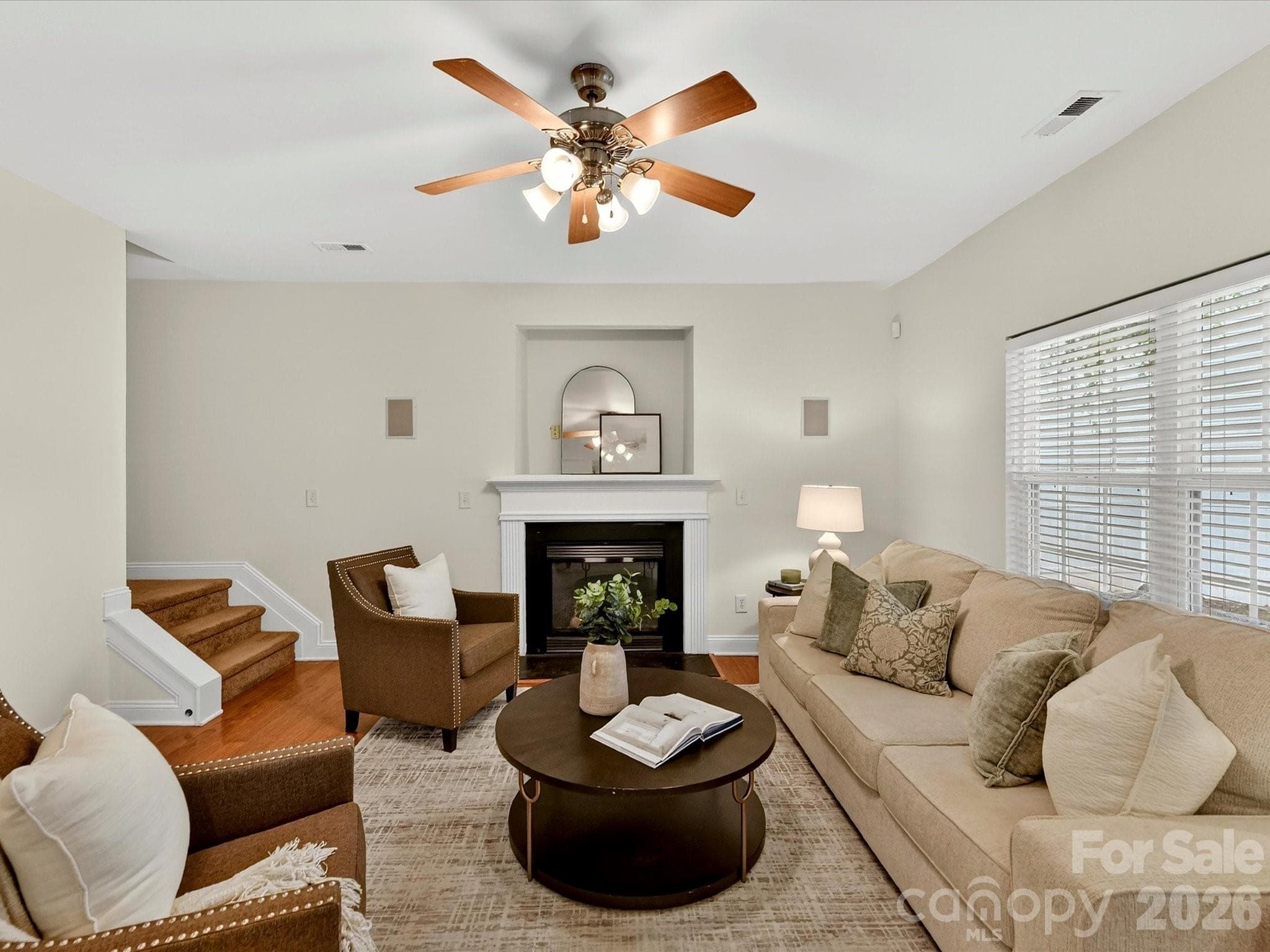 Spacious great room features wood flooring, a cozy fireplace with classic mantel, and an open-concept layout designed for comfortable everyday living and effortless entertaining. - Cornelius