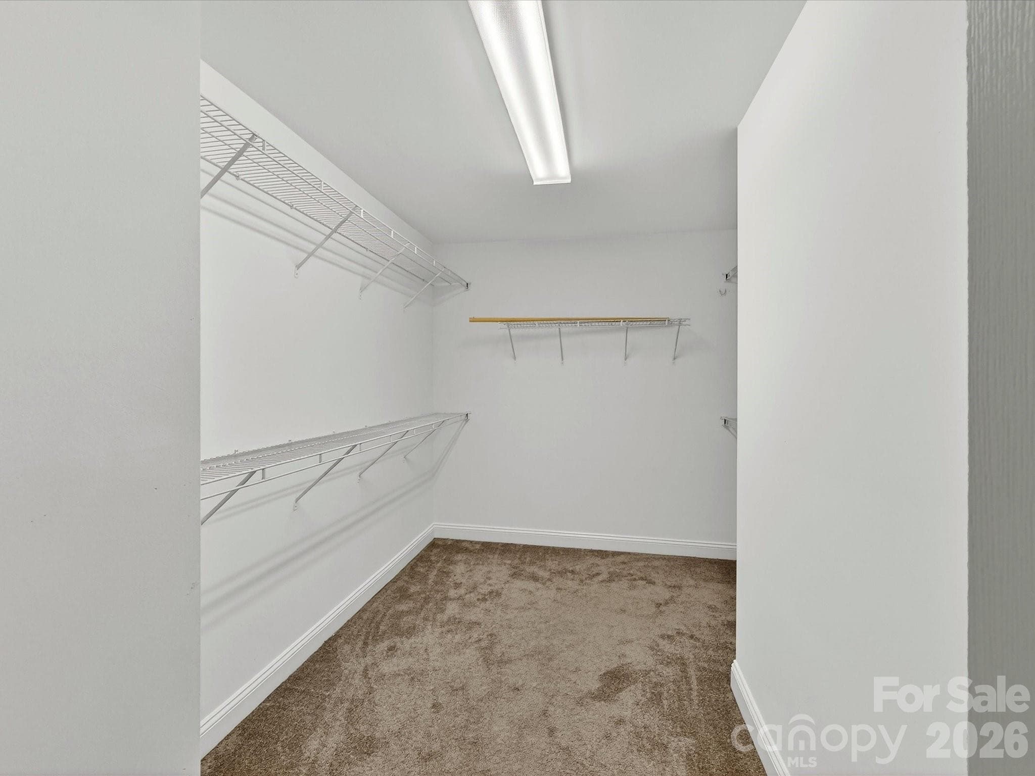 Generously sized walk-in closet offers ample storage and organization space with multiple shelving areas designed to accommodate an extensive wardrobe. - Cornelius