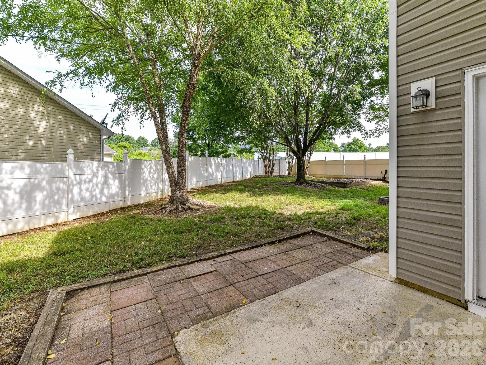 Private fenced backyard features mature shade trees, a patio area for outdoor entertaining, and a dedicated fire pit gathering space, creating the perfect setting for relaxation and recreation. - Cornelius