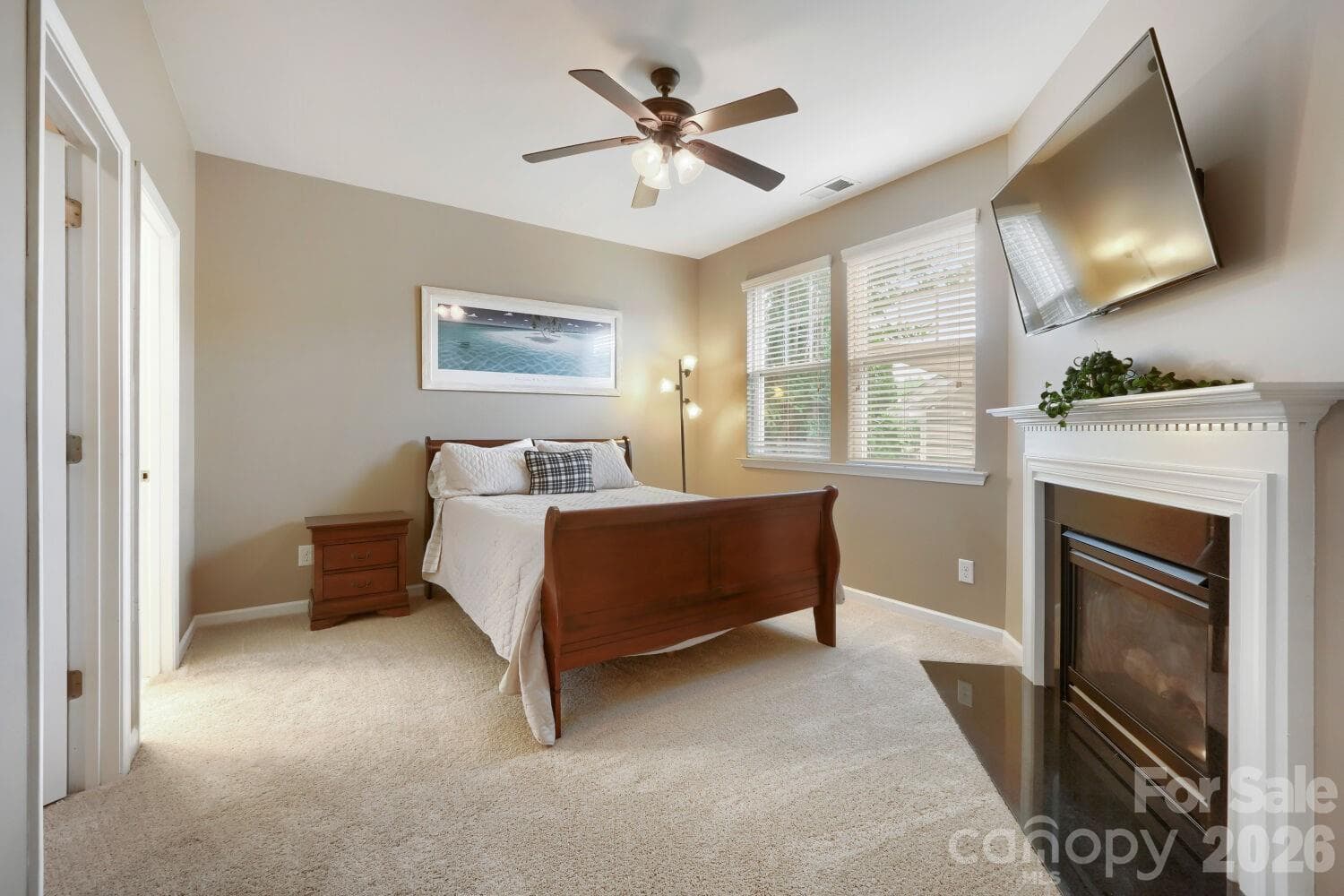 The main-level bedroom suite offers a peaceful retreat with a cozy fireplace — a quiet space to start and end the day. suite, showcasing the warm tones, plush carpet, and tranquil layout. - Huntersville