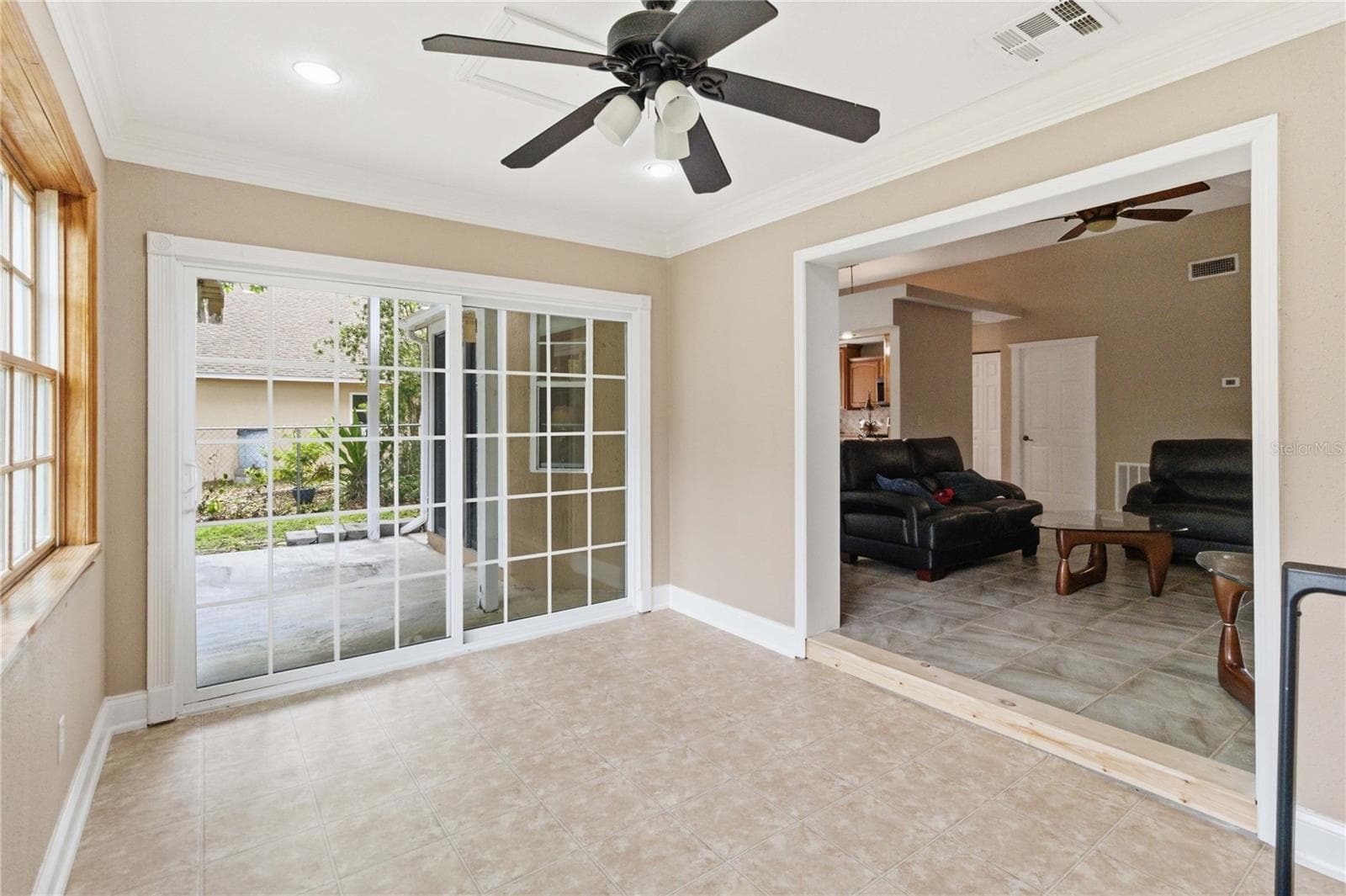 Bonus room features ceramic tile floors, crown molding, and sliding doors lead to a covered patio and backyard - 1564 CYPRESS WOODS CIR, ST CLOUD