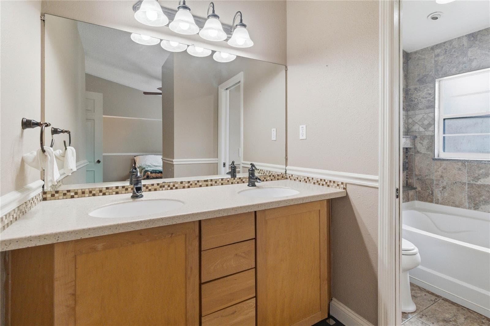Ensuite primary bathroom with dual sinks and pocket door to tub/shower. - 1564 CYPRESS WOODS CIR, ST CLOUD