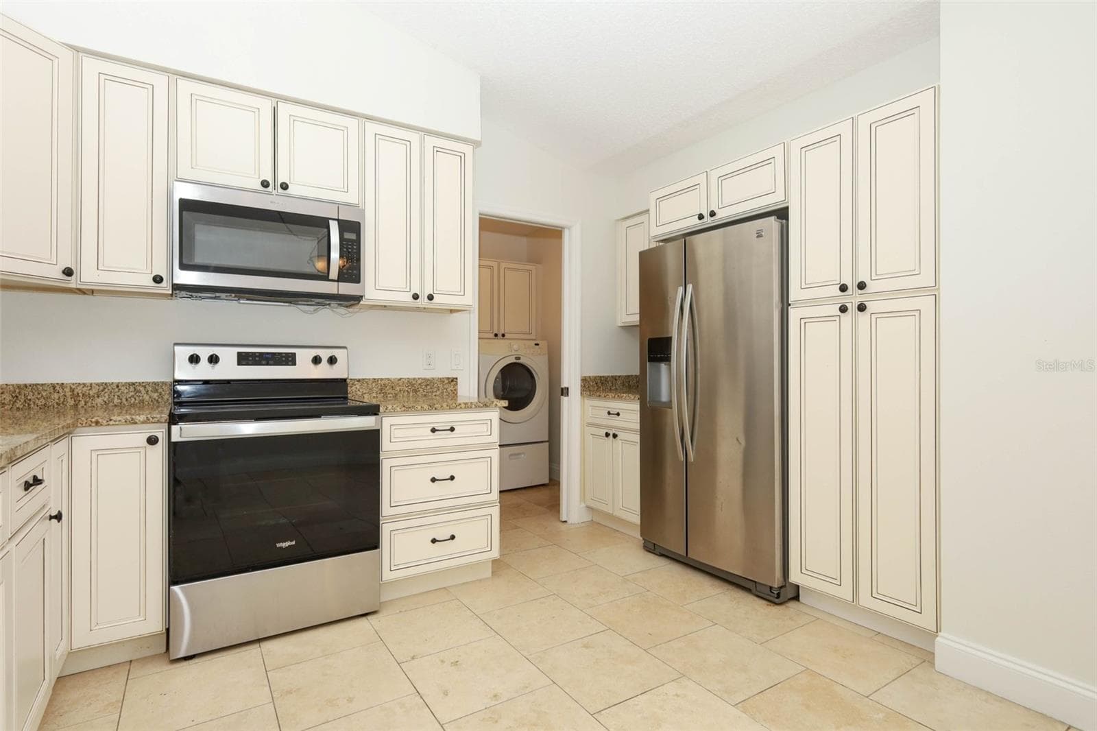 Spacious kitchen with travertine tile flooring, granite countertops and stainless steel appliances. - 9110 PALM TREE DR, WINDERMERE