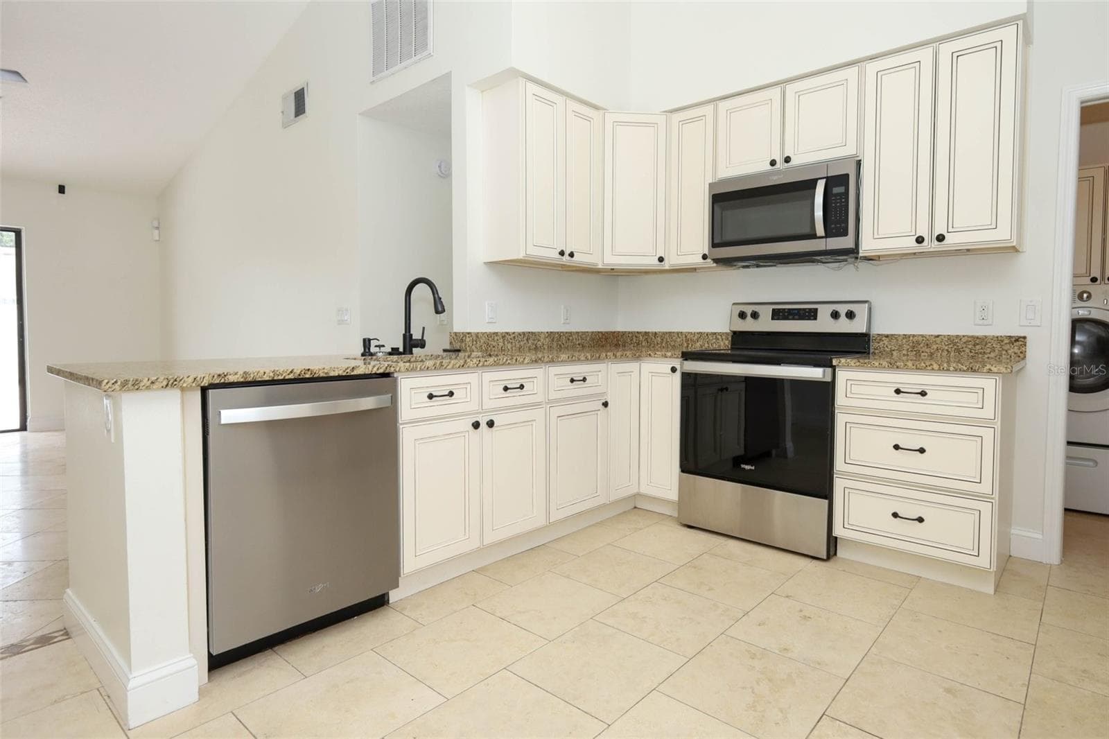 Spacious kitchen with travertine tile flooring, granite countertops and stainless steel appliances. - 9110 PALM TREE DR, WINDERMERE