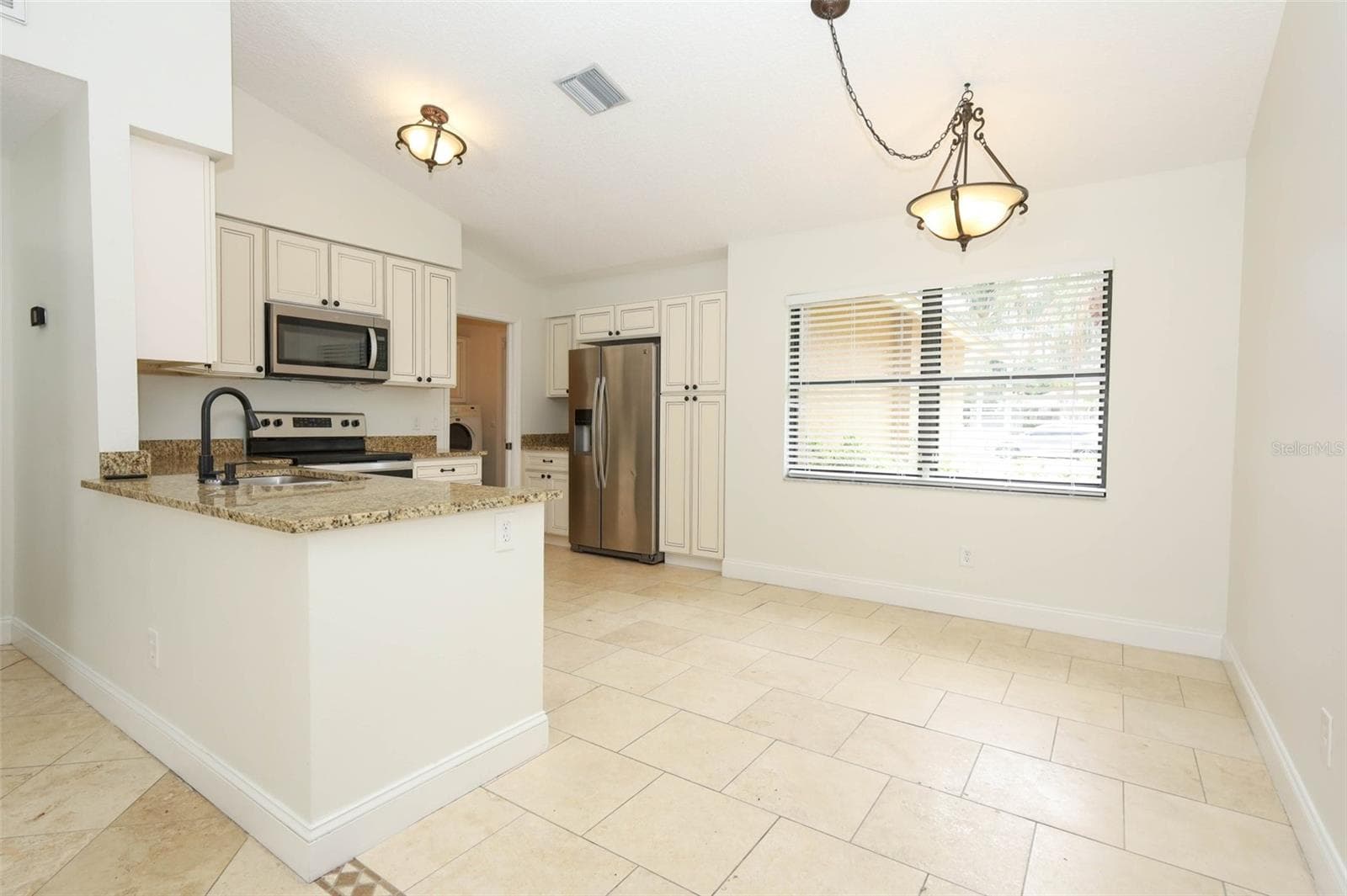 Spacious kitchen with travertine tile flooring, granite countertops and stainless steel appliances. - 9110 PALM TREE DR, WINDERMERE