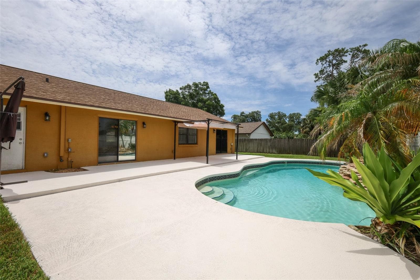 Rear yard with an open-air sparkling pool with space for the kids and pets to play. - 9110 PALM TREE DR, WINDERMERE