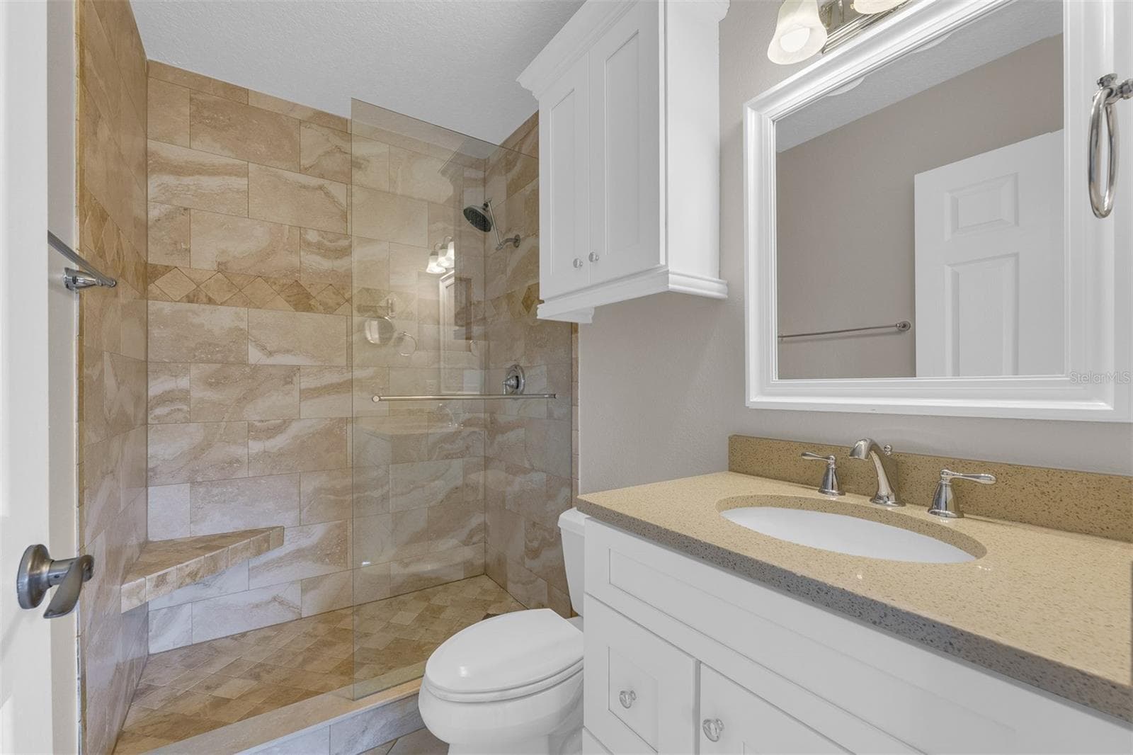 Primary ensuite bathroom with beautiful travertine tile. - 110 N TREMAIN ST #209, MOUNT DORA