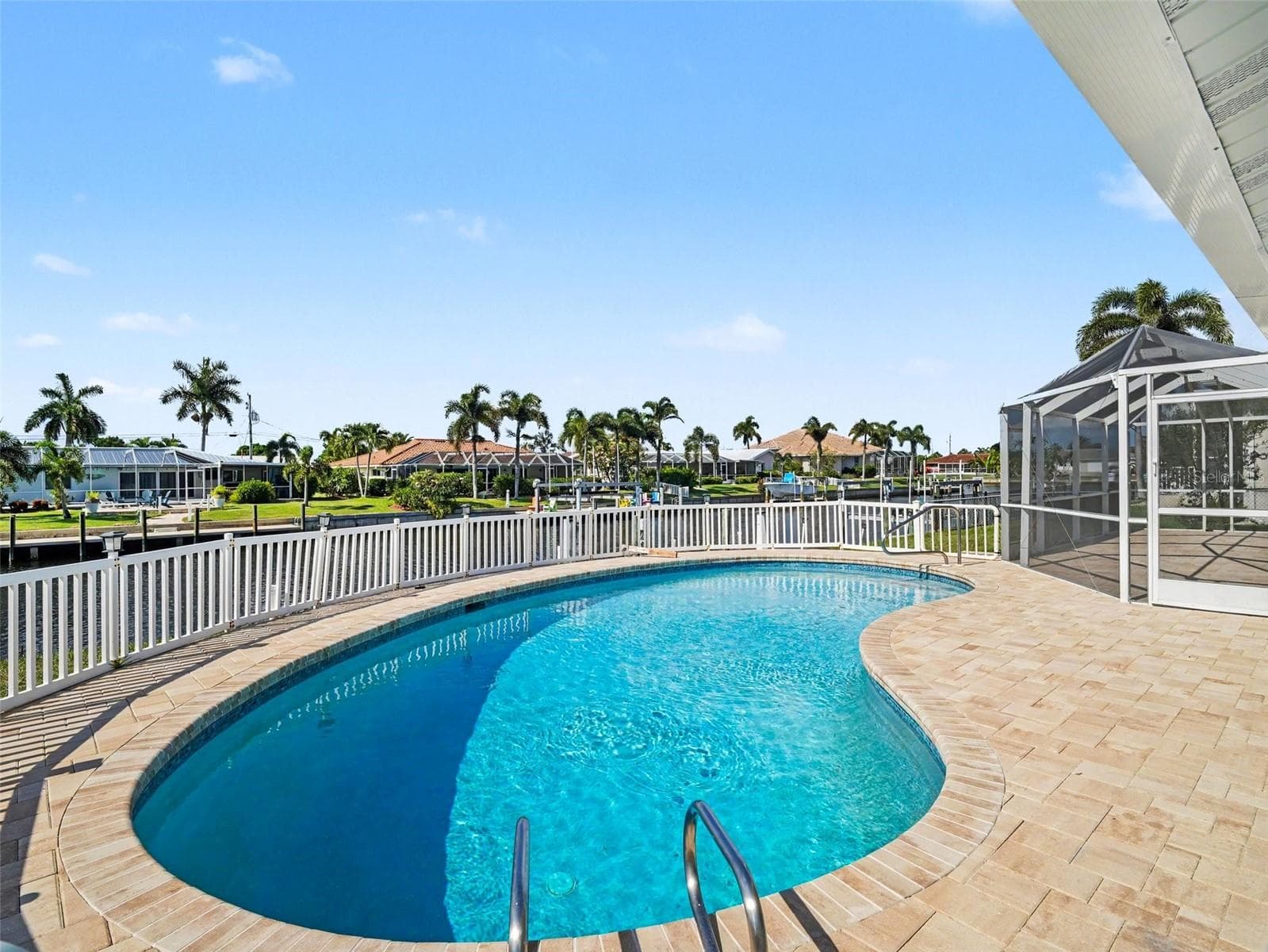 Open air pool with new deck pavers and beautiful views of the water, palm trees and waterfront homes - 548 BELVEDERE CT, PUNTA GORDA
