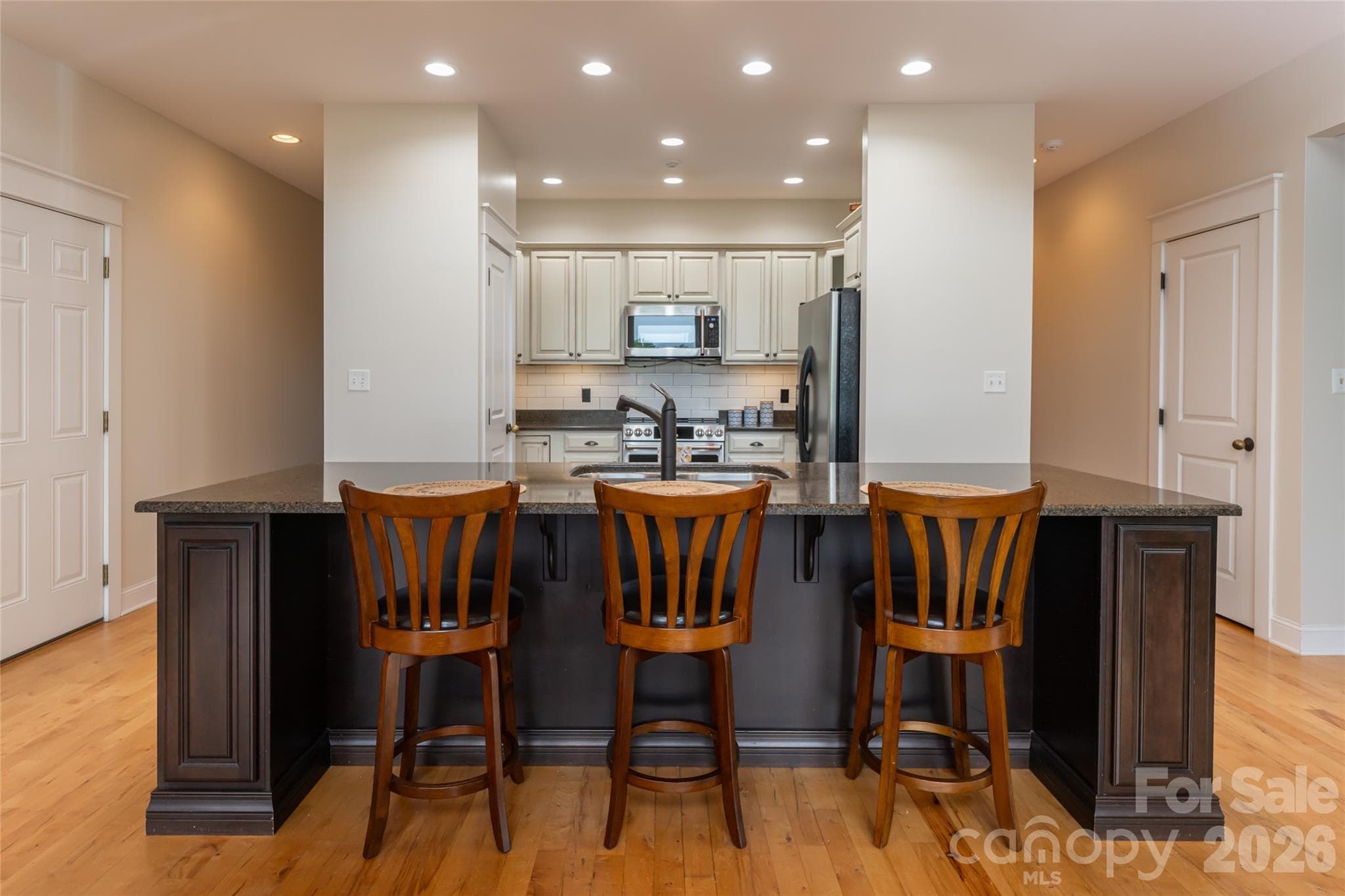 Well-appointed kitchen featuring granite countertops, a center island, an induction oven, premium stainless steel appliances, and classic subway tile backsplash. - 33 Bridle Path Drive, Barnardsville