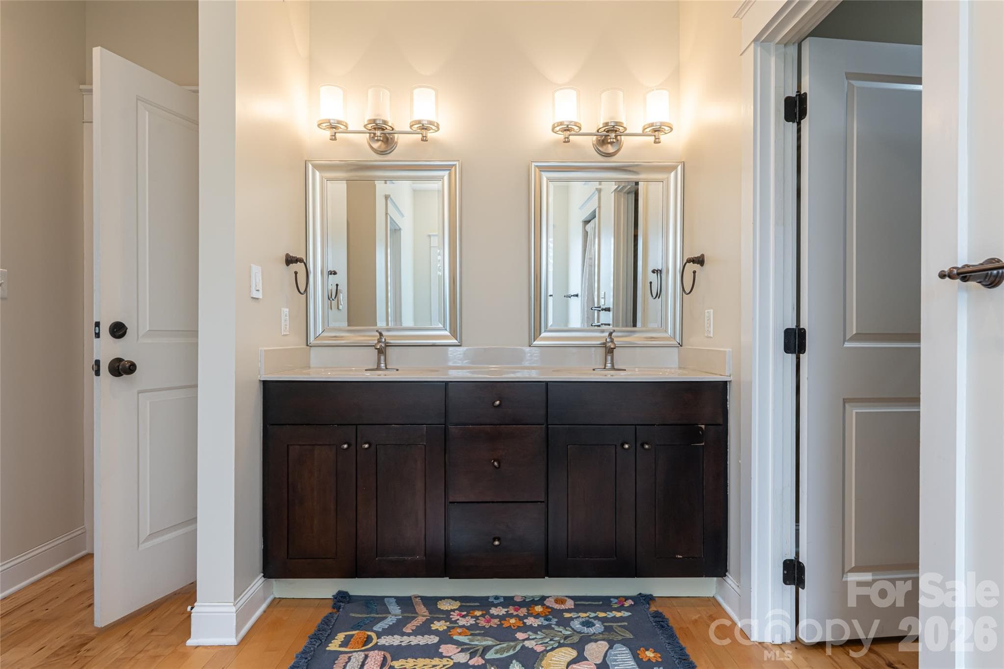 The main level primary suite features a luxurious en-suite bathroom with dual vanities, a jetted tub, an oversized tile shower, and a spacious walk-in closet. - 33 Bridle Path Drive, Barnardsville