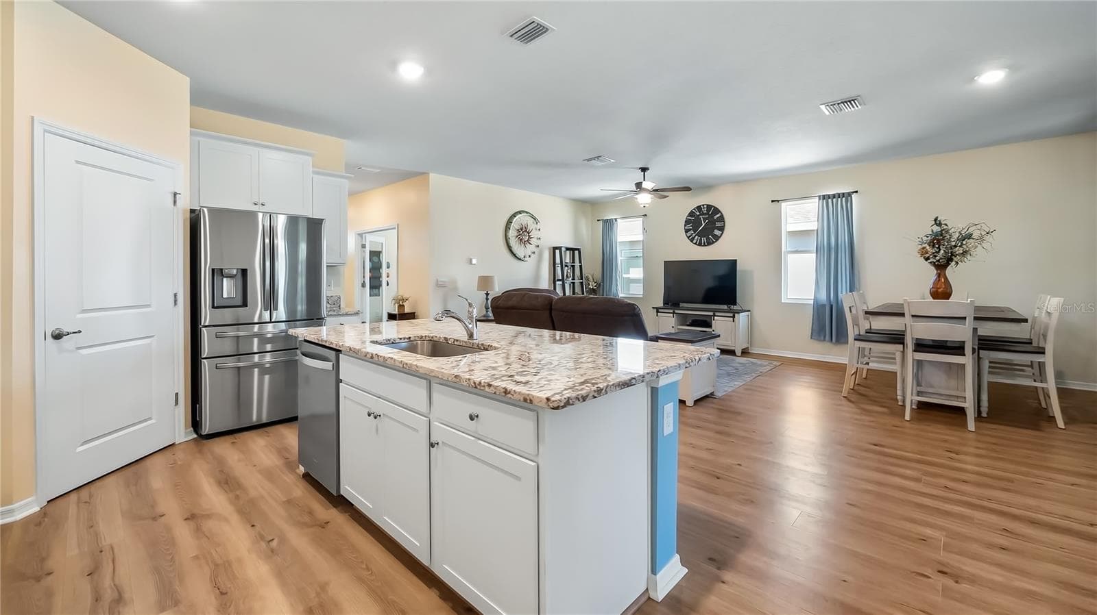 The kitchen is equipped with stainless steel appliances, granite countertops, and a breakfast bar overlooking the living room and dining room. - 8033 PENROSE PL, WILDWOOD