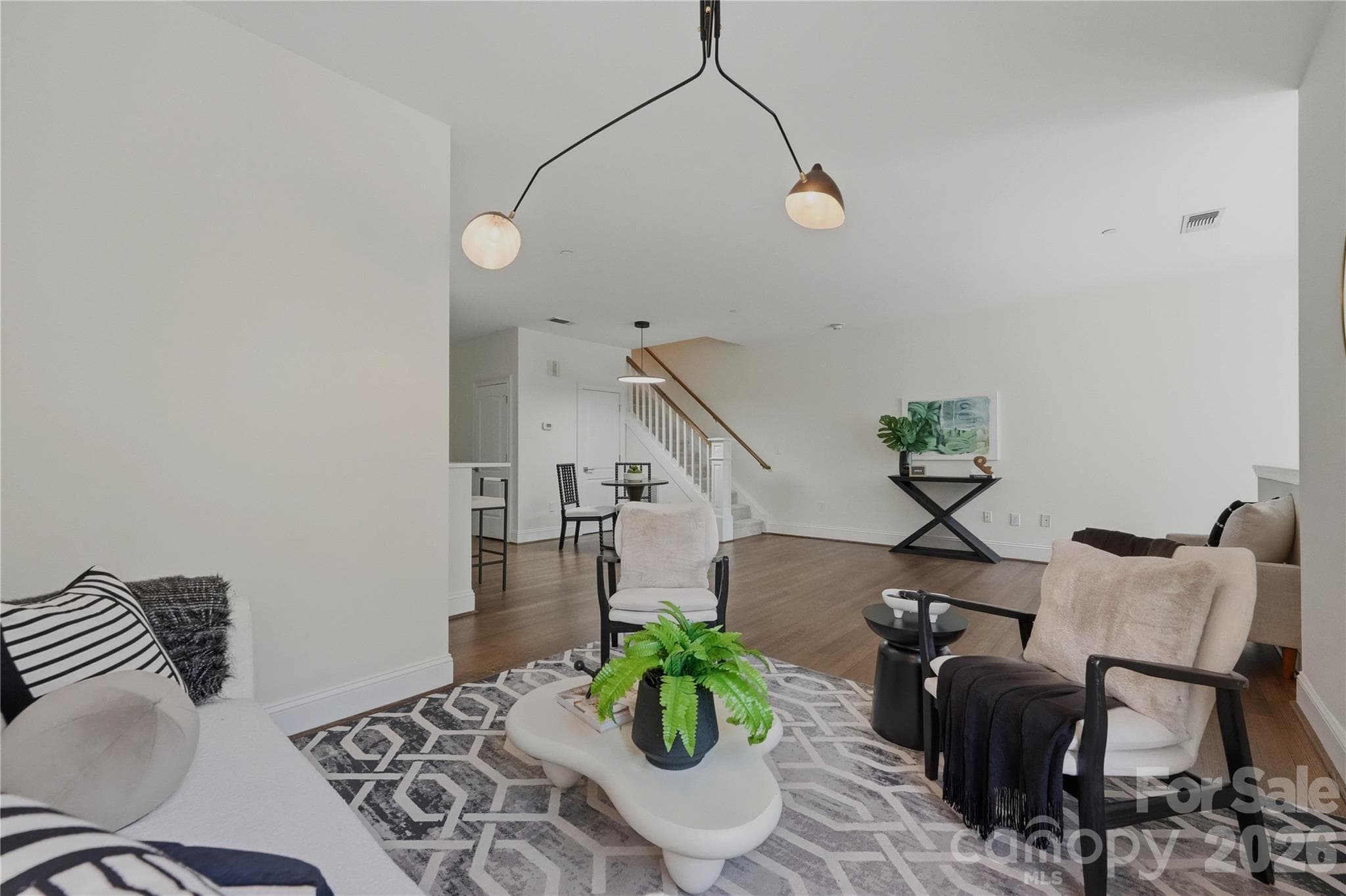 Statement lighting, a sculptural coffee table, and an open sight line all the way to the staircase make this living room designed to impress from every angle. - Charlotte