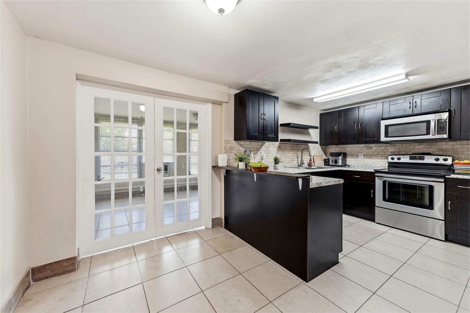 Kitchen with double doors that lead back to the third bedroom. This can also be used as an office, Florida room or extra living room. Endless possiblities. - 3849 LUMA DR, HOLIDAY