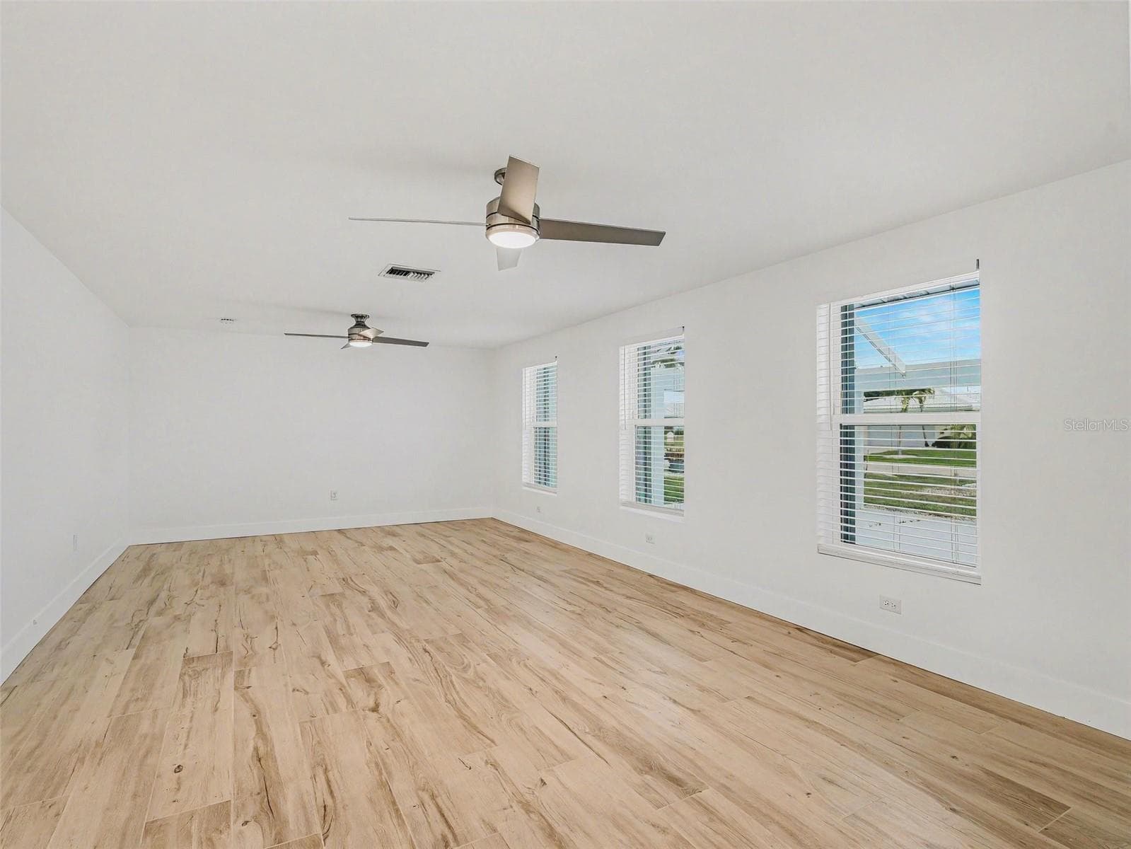 Large living room with multiple windows and ceiling fans, overlooking the front courtyard - 548 BELVEDERE CT, PUNTA GORDA