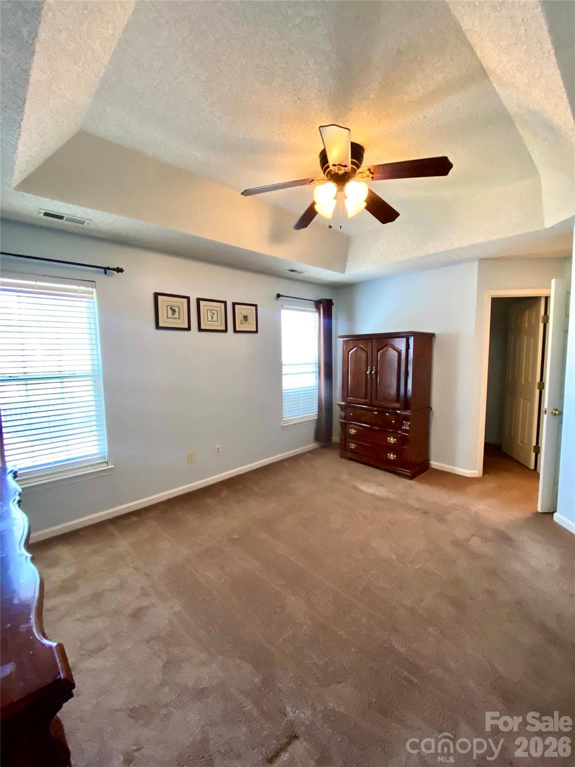 Primary Bedroom with tray ceiling and ceiling light/fan. - 6025 Creft Circle, Indian Trail