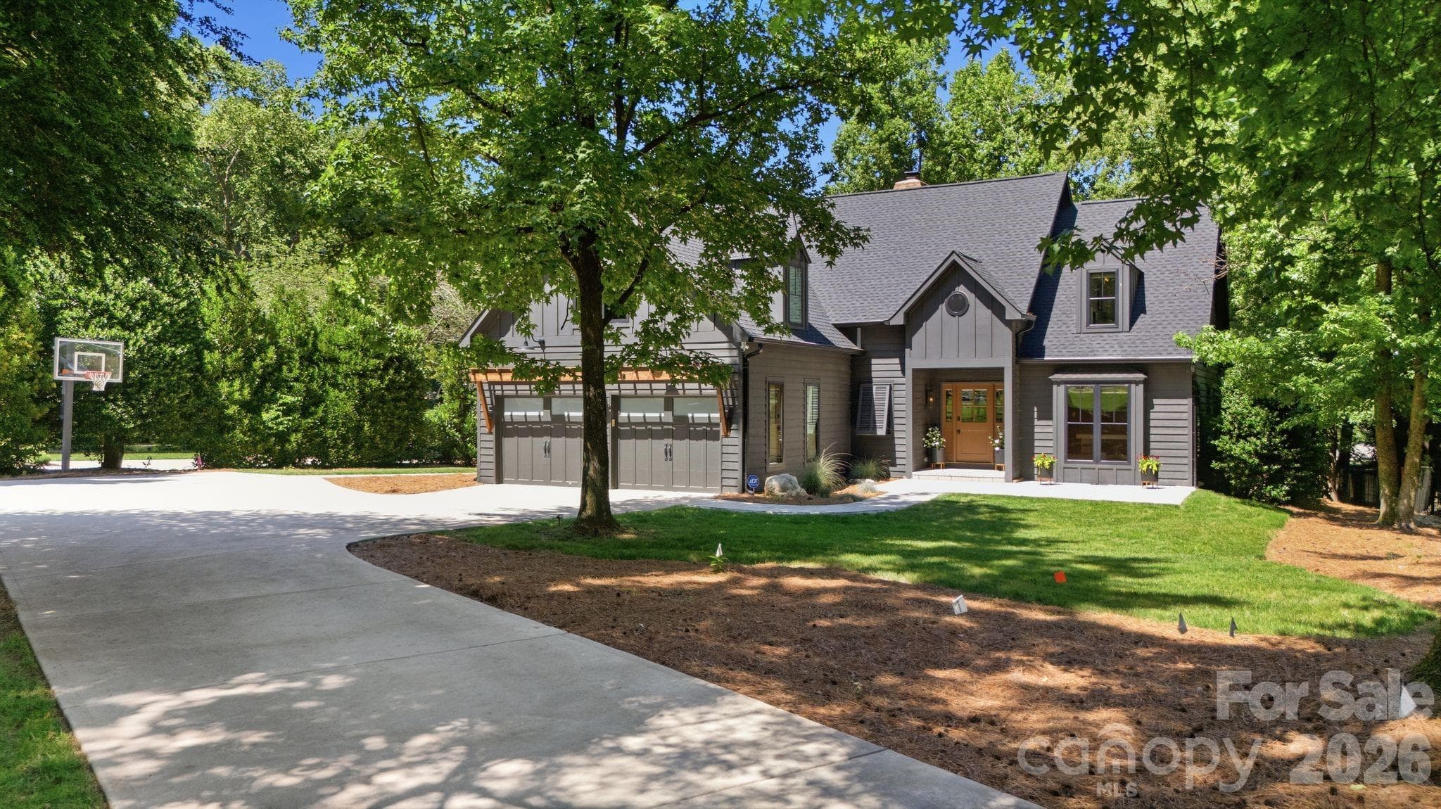 Wide driveway and attached two-car garage create convenient everyday functionality. The front elevation shows a well-maintained exterior with mature landscaping and a private setting. - Cornelius