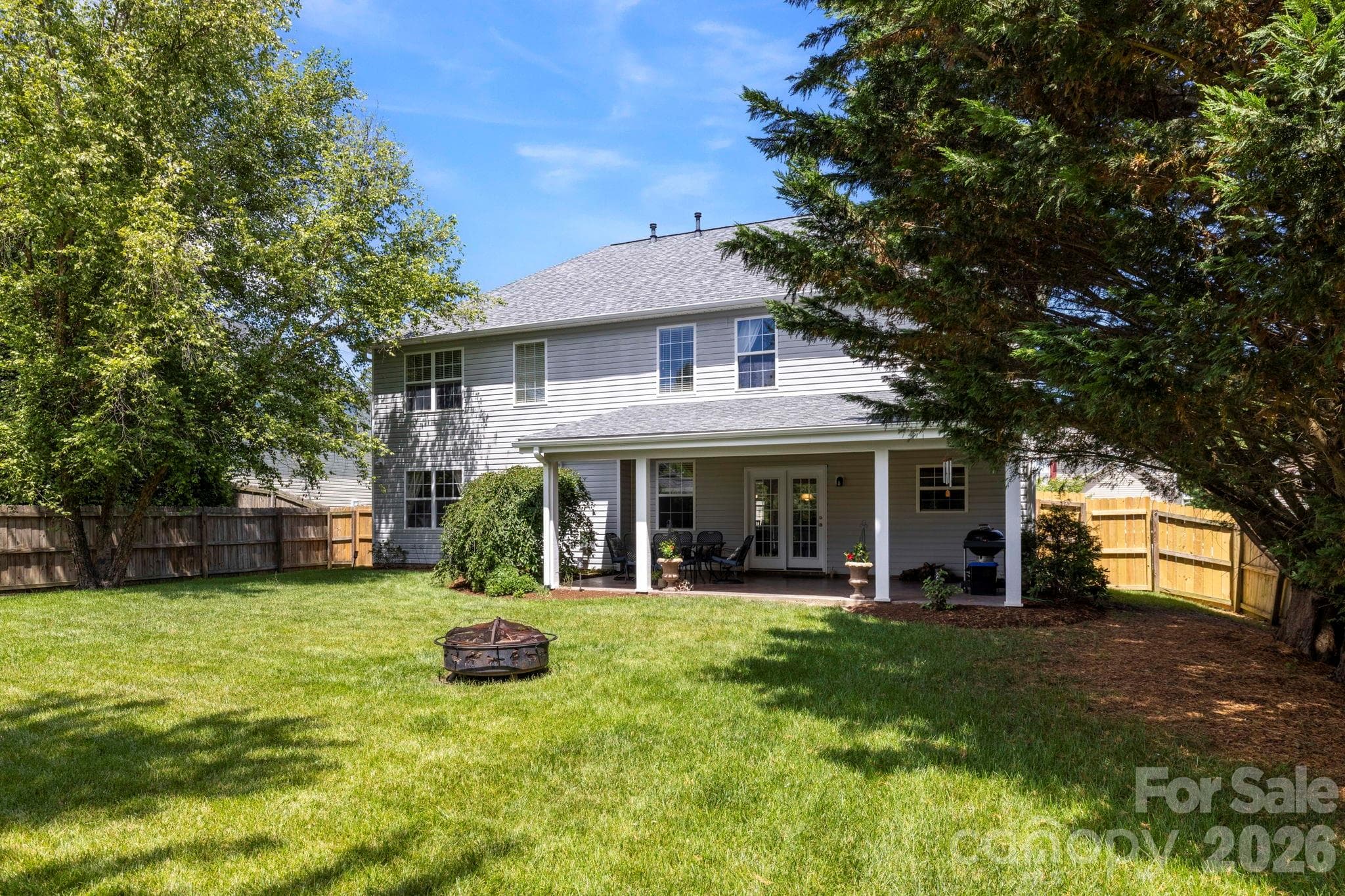 Rear view of the home highlighting the covered outdoor living area and spacious backyard setting. - Fletcher