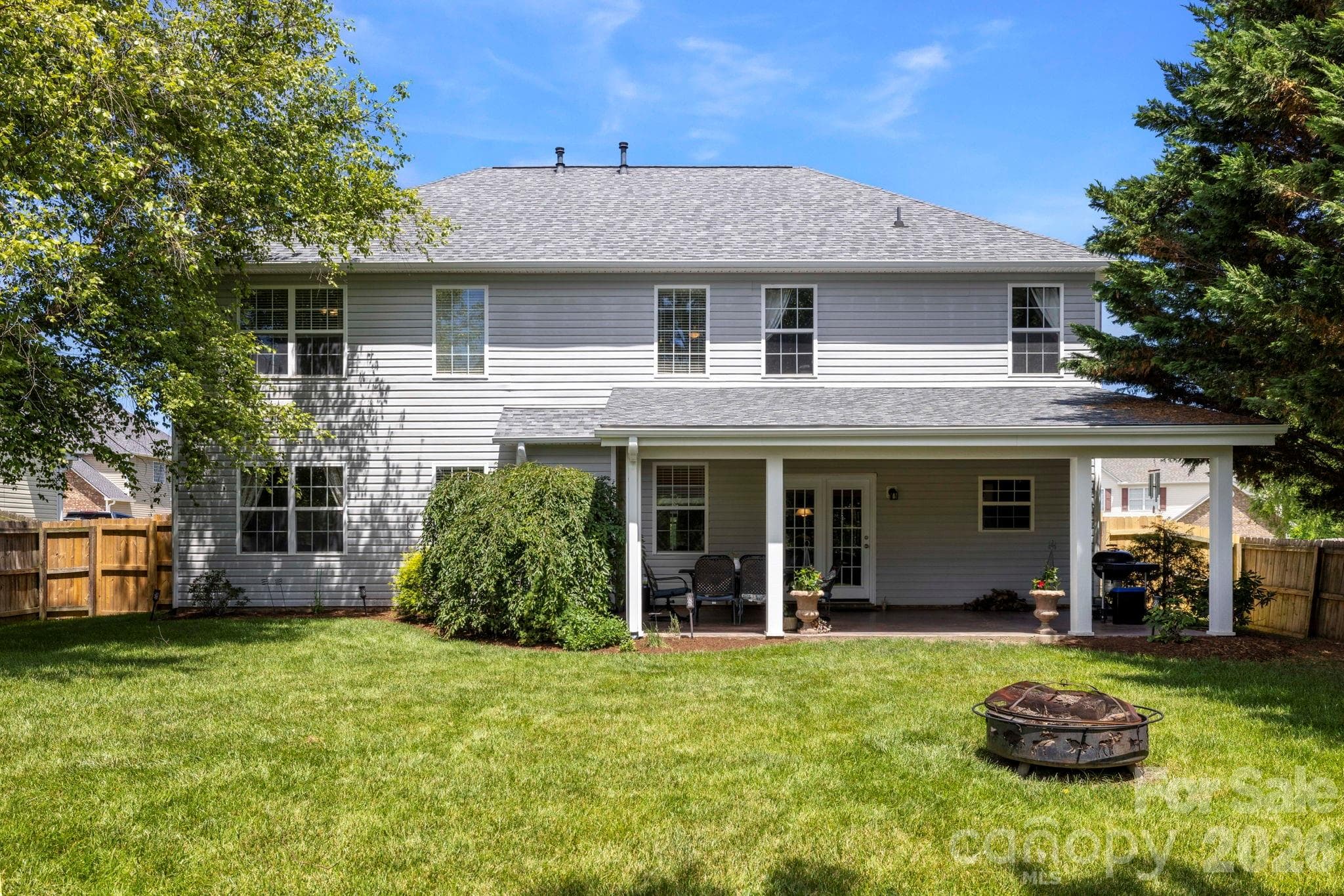 Fully fenced backyard featuring a large lawn and covered patio, offering plenty of room for outdoor activities and gatherings. - Fletcher