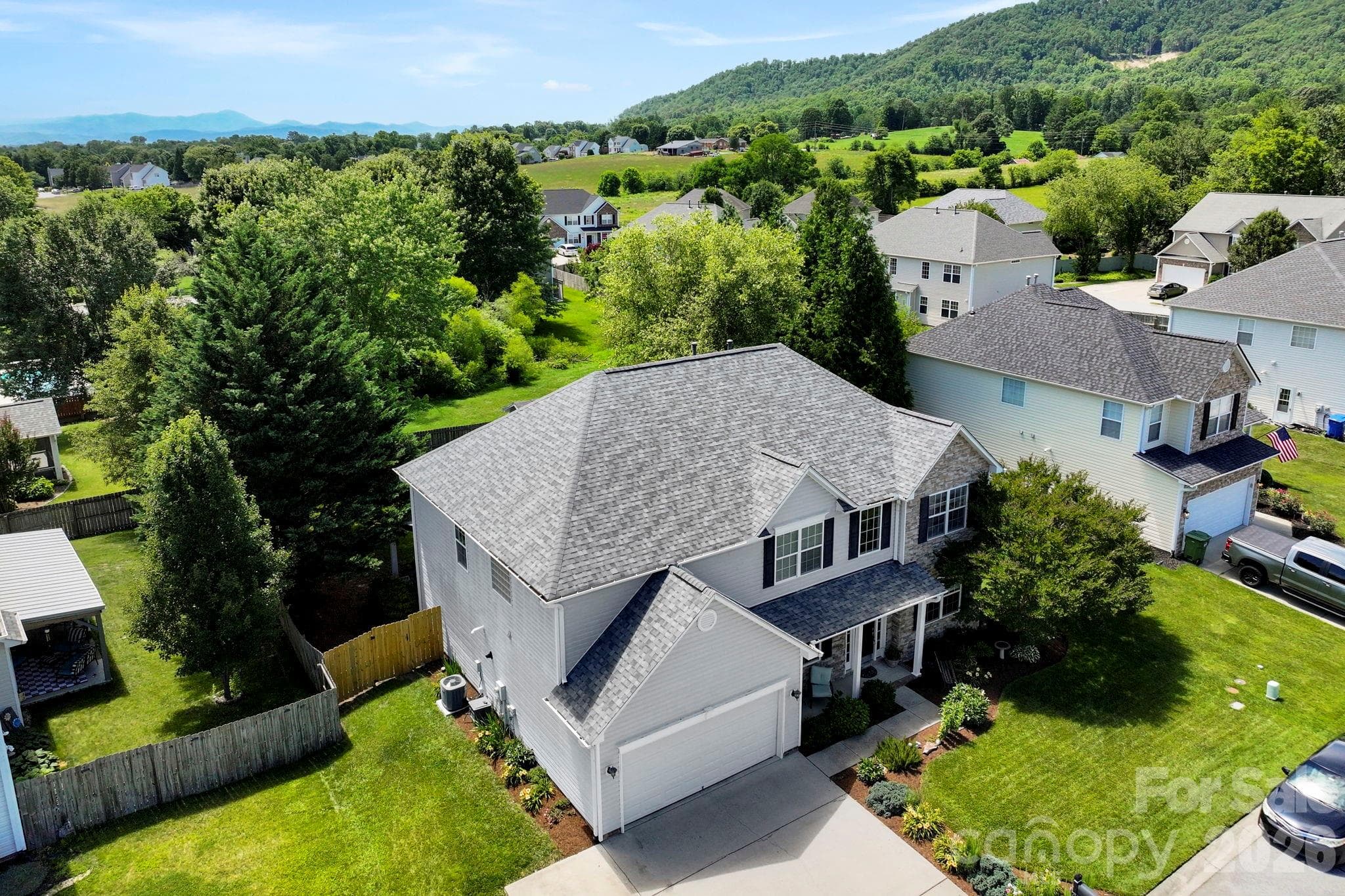 Elevated aerial view showcasing the home’s attractive curb appeal, landscaped lot, and surrounding mountain backdrop. - Fletcher