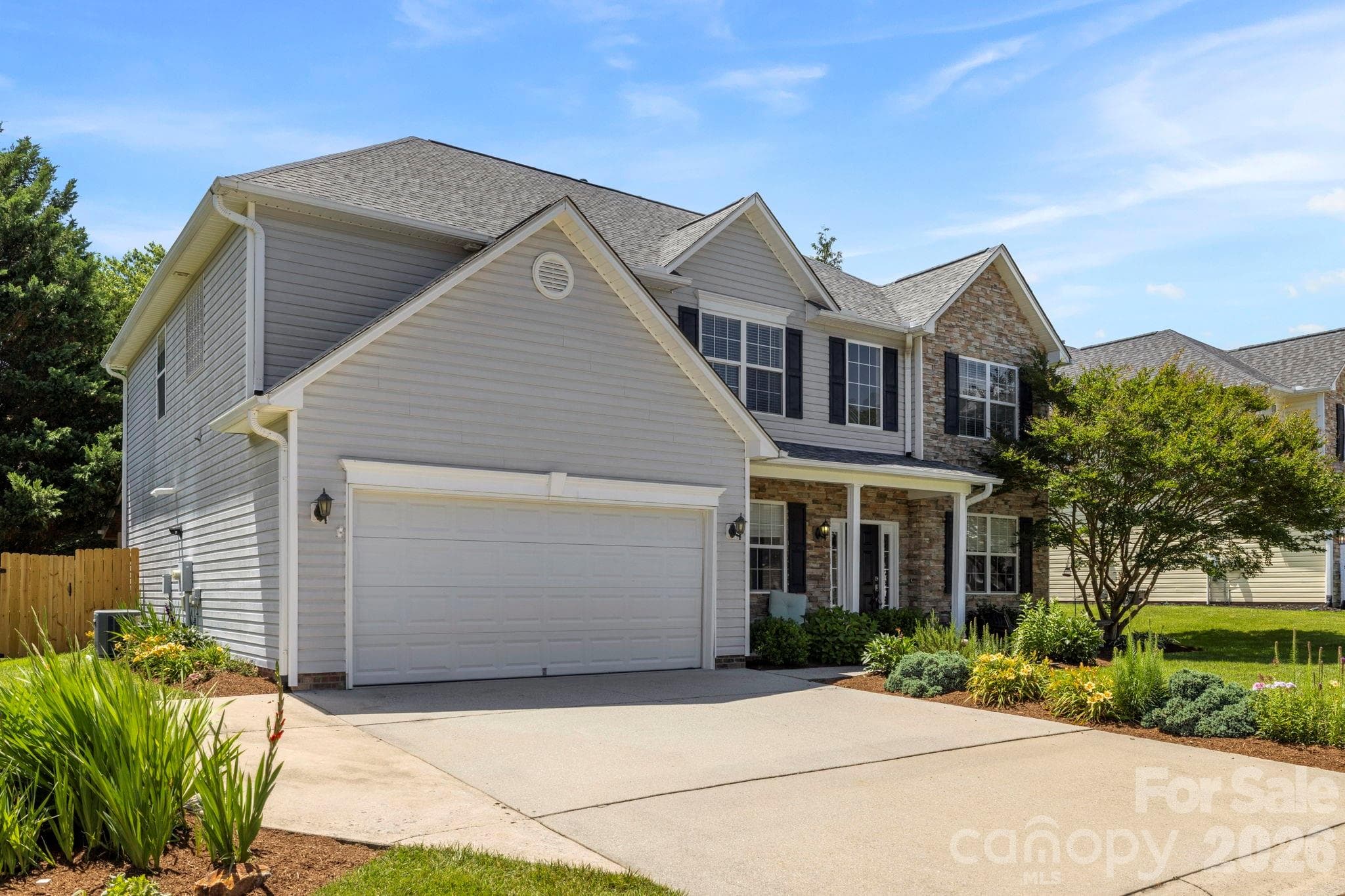 Spacious driveway leading to a two-car garage, complemented by mature landscaping and charming architectural details. - Fletcher
