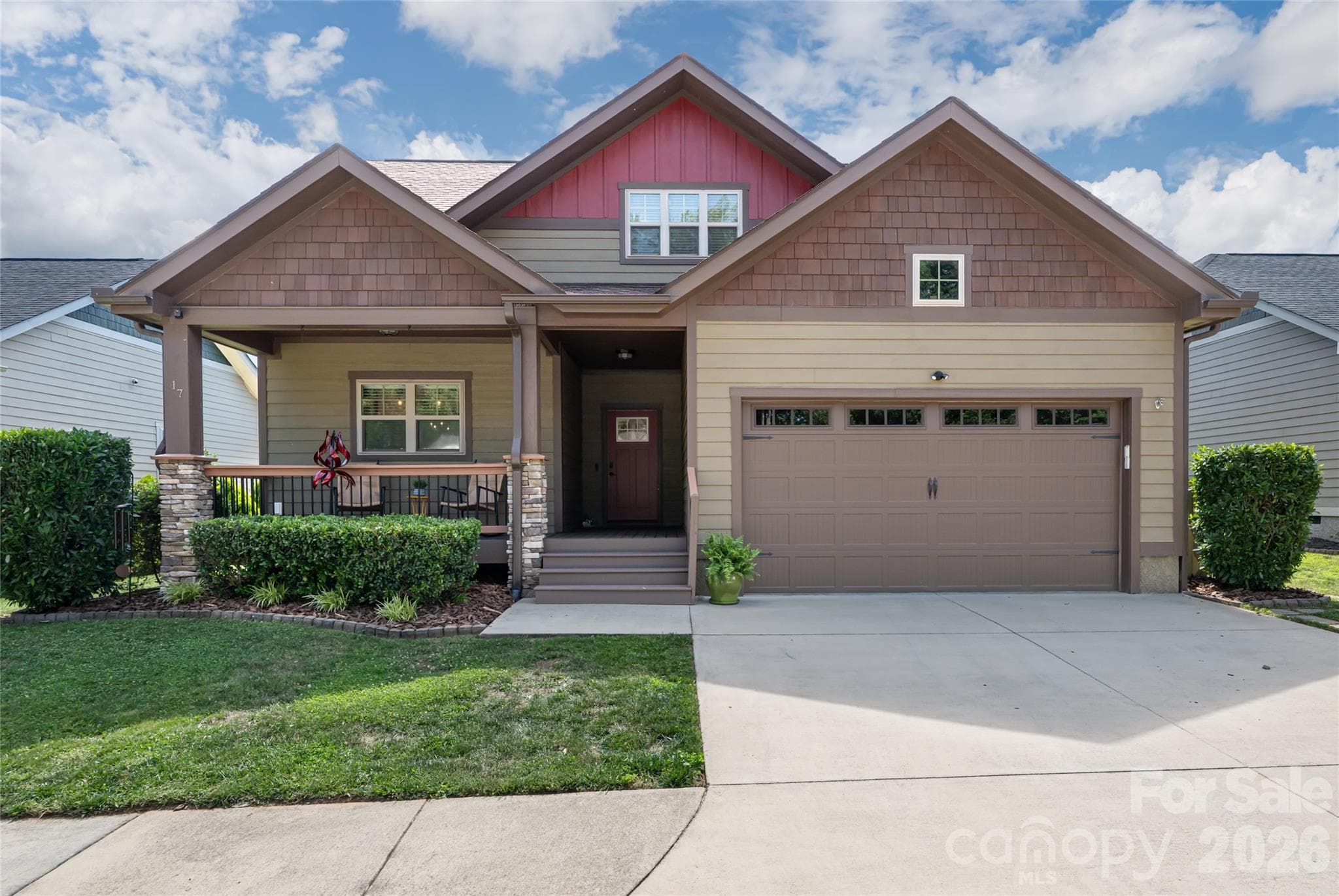 Front elevation showing the attached two-car garage, concrete driveway, and covered craftsman entry of this 2015-built South Asheville home. - Arden