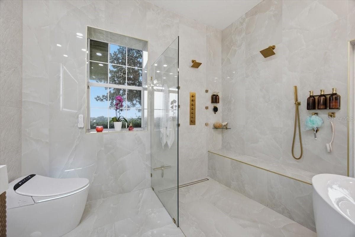 Resort-inspired spa shower featuring an oversized walk-in design with dual rainfall shower heads, multiple body spray jets, a handheld wand, an expansive built-in tiled bench, frameless glass enclosure, and floor-to-ceiling porcelain tile for a truly luxurious experience. - 915 N CROOKED LAKE DR, BABSON PARK