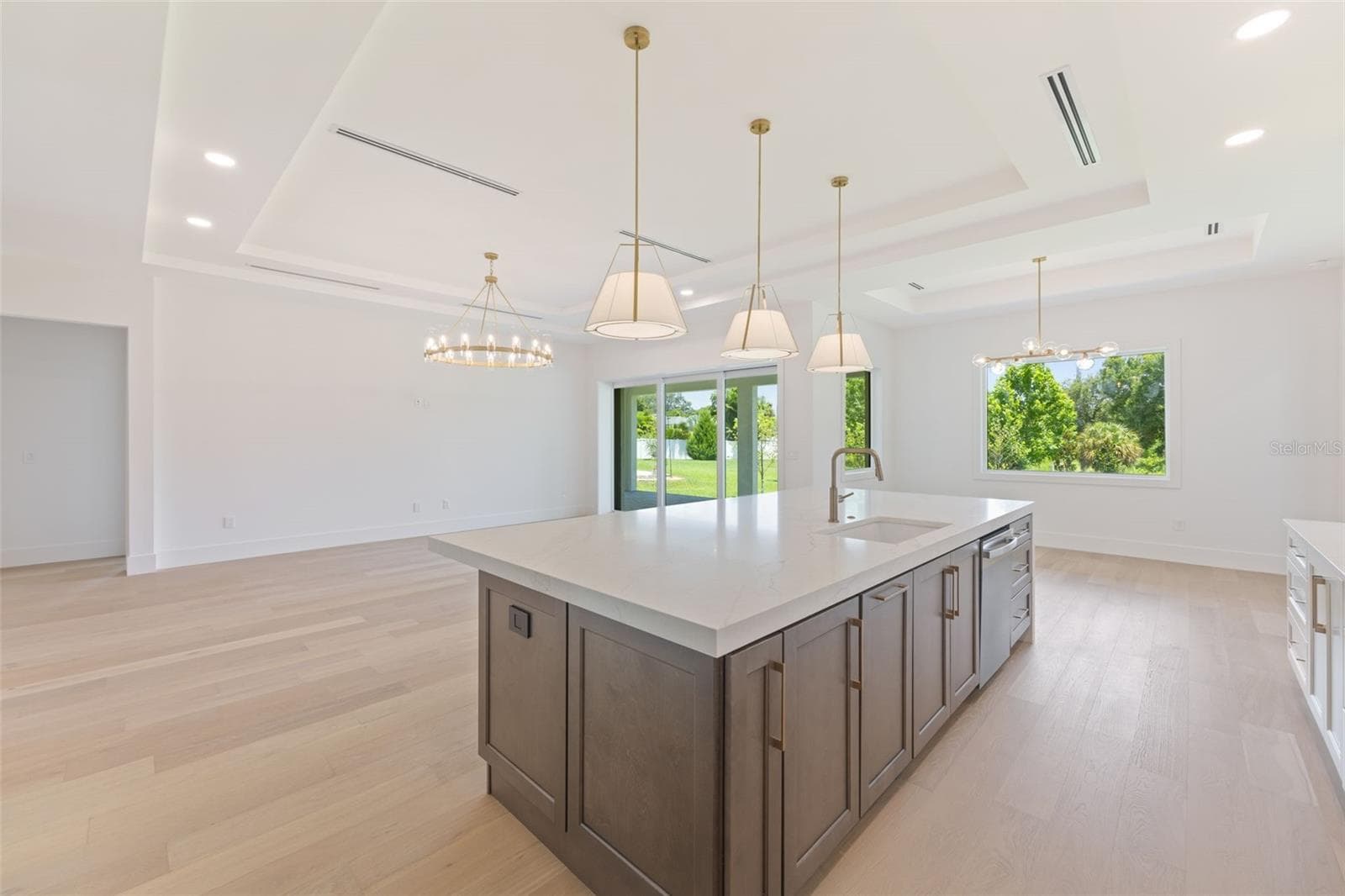 The gourmet kitchen is a true showpiece, featuring full-height custom cabinetry, an oversized 11-foot quartz island with storage on both sides, marble backsplash, GE Profile appliances, custom range hood, cooktop, wall oven, and soft-close cabinetry throughout. - 1336 HAYS RD, TARPON SPRINGS