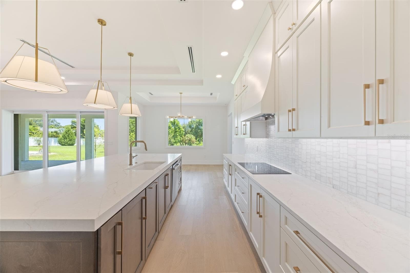 The gourmet kitchen is a true showpiece, featuring full-height custom cabinetry, an oversized 11-foot quartz island with storage on both sides, marble backsplash, GE Profile appliances, custom range hood, cooktop, wall oven, and soft-close cabinetry throughout. - 1336 HAYS RD, TARPON SPRINGS