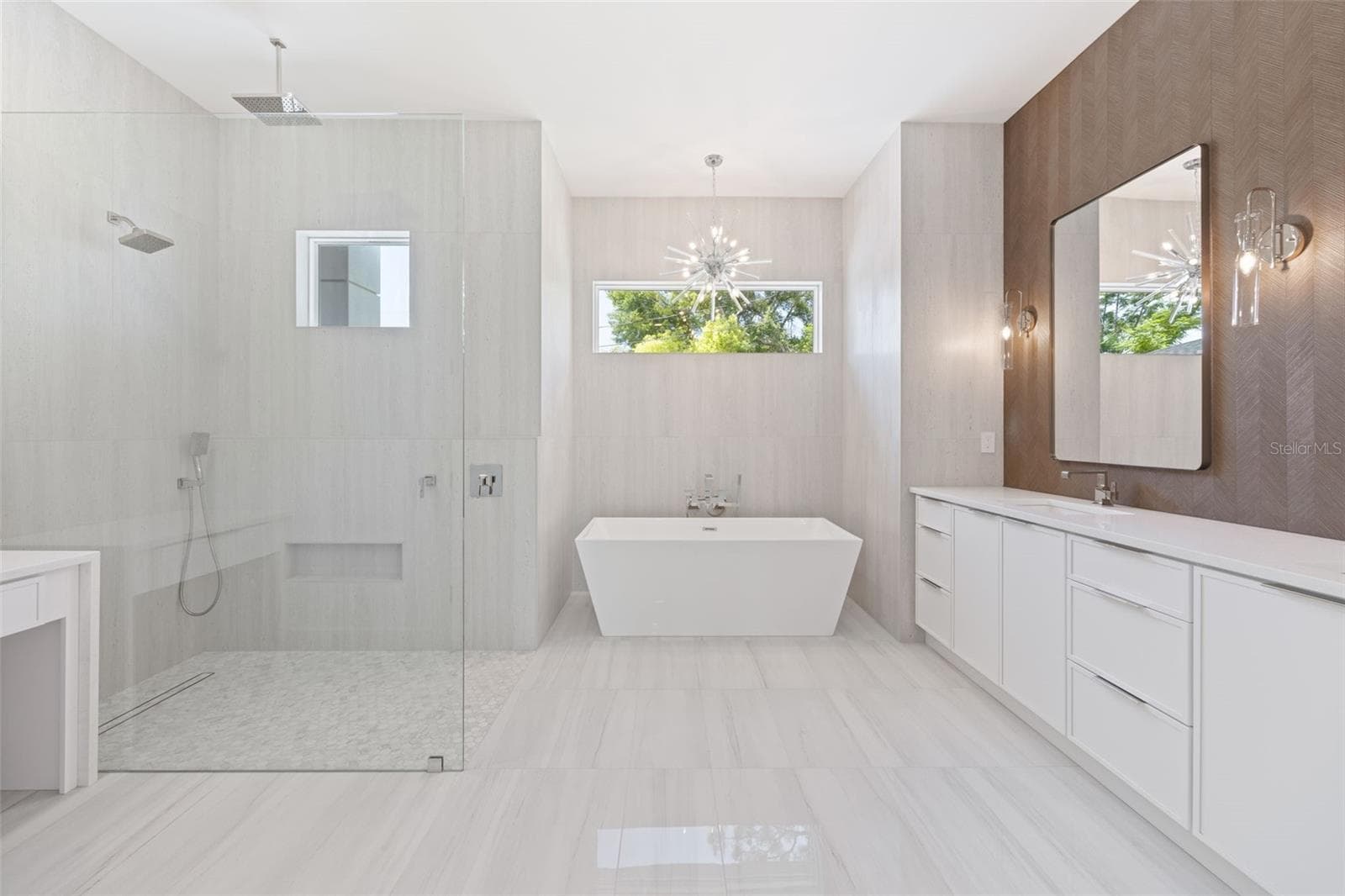 The luxurious primary suite offers a spa-inspired retreat featuring a freestanding soaking tub, oversized walk-in shower with rain head and handheld shower, premium Italian tile, designer fixtures, and thoughtful custom details throughout. - 1336 HAYS RD, TARPON SPRINGS