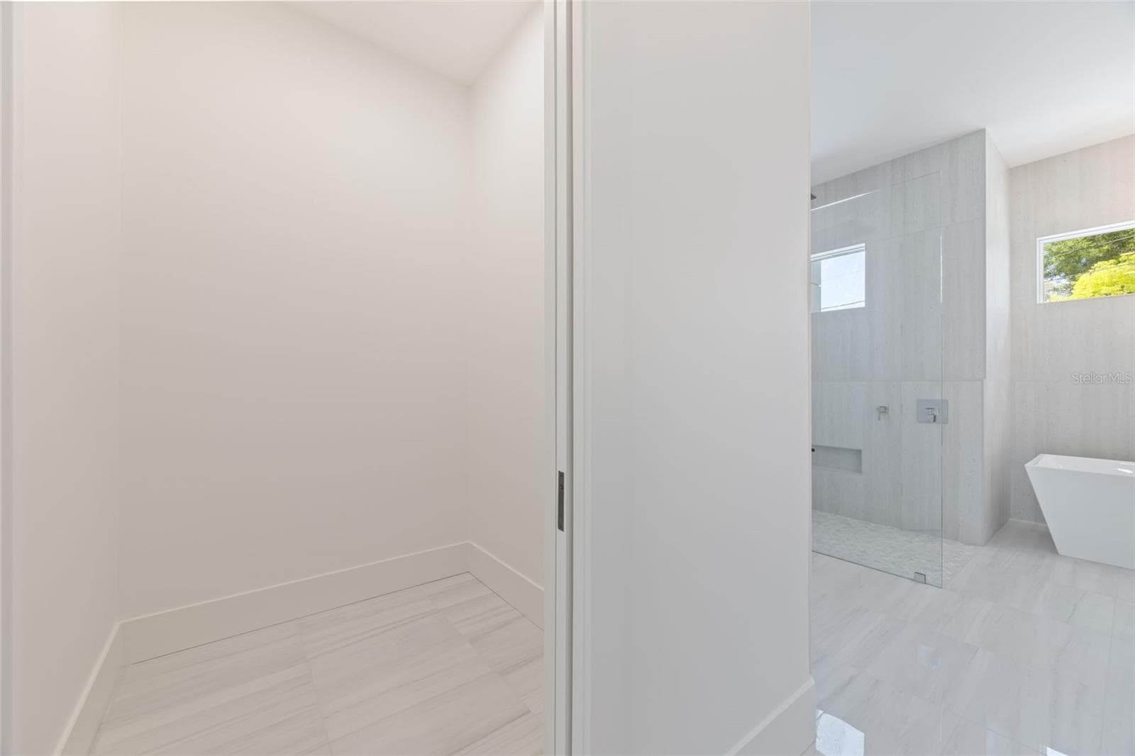 The luxurious primary suite offers a spa-inspired retreat featuring a freestanding soaking tub, oversized walk-in shower with rain head and handheld shower, premium Italian tile, designer fixtures, and thoughtful custom details throughout. - 1336 HAYS RD, TARPON SPRINGS
