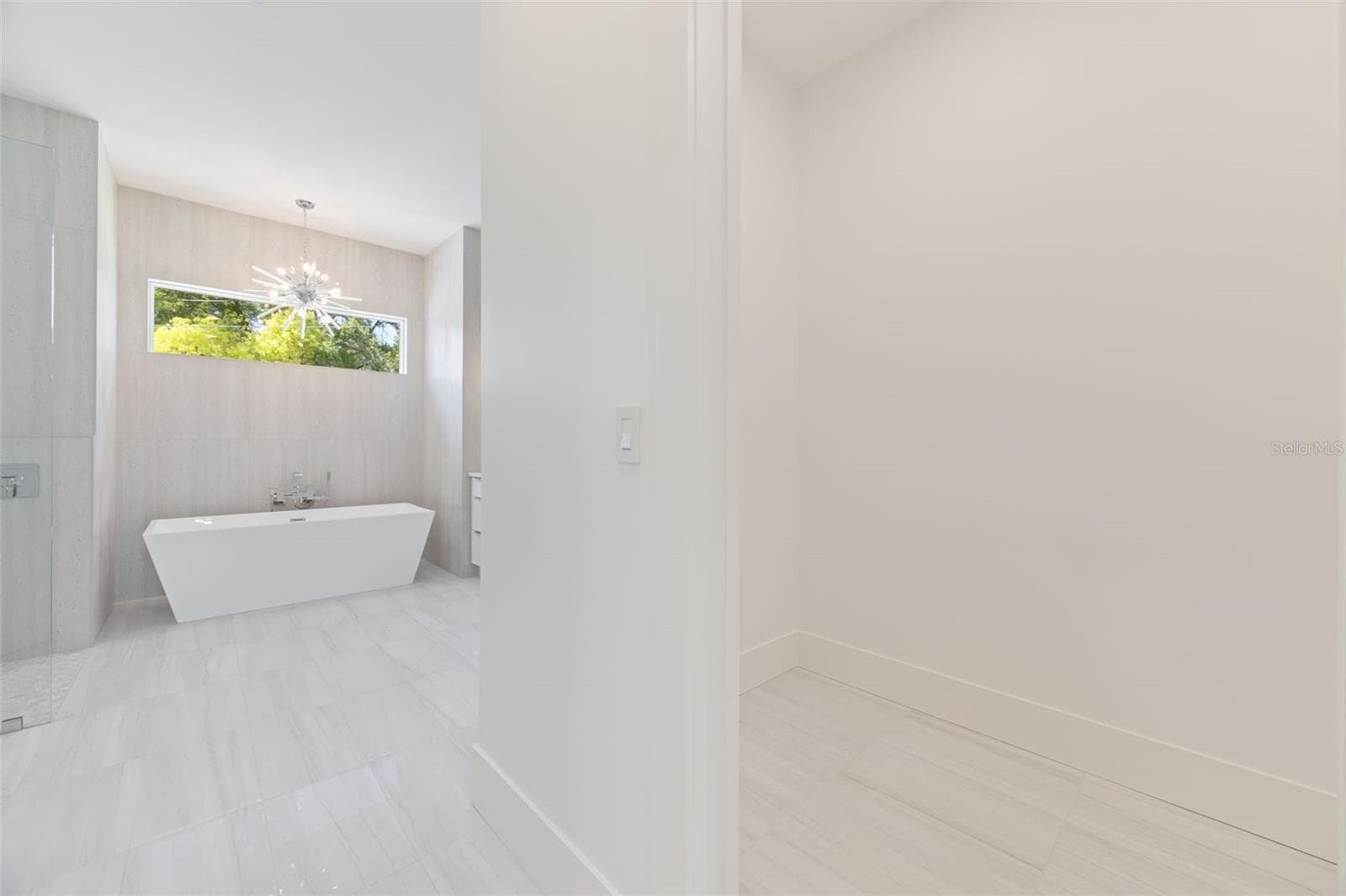 The luxurious primary suite offers a spa-inspired retreat featuring a freestanding soaking tub, oversized walk-in shower with rain head and handheld shower, premium Italian tile, designer fixtures, and thoughtful custom details throughout. - 1336 HAYS RD, TARPON SPRINGS