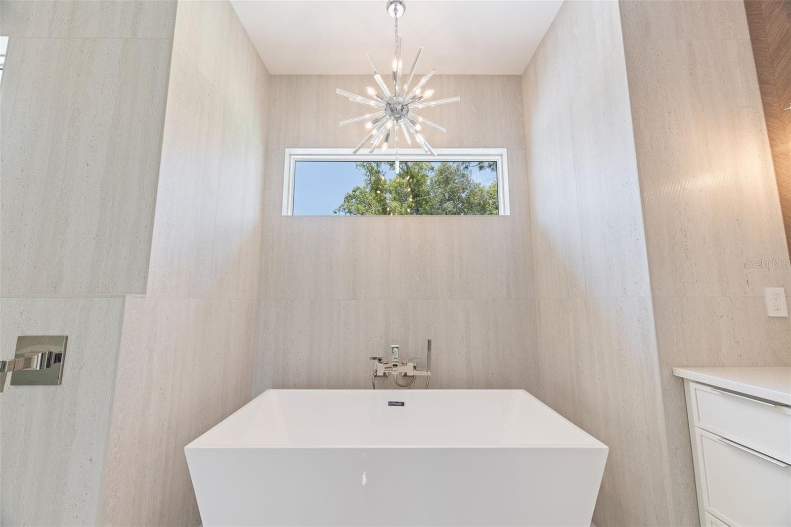 The luxurious primary suite offers a spa-inspired retreat featuring a freestanding soaking tub, oversized walk-in shower with rain head and handheld shower, premium Italian tile, designer fixtures, and thoughtful custom details throughout. - 1336 HAYS RD, TARPON SPRINGS