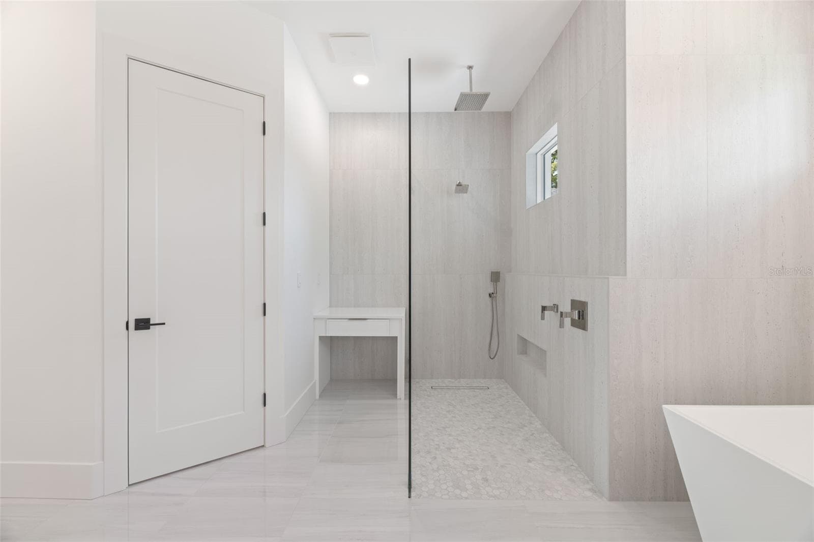 The luxurious primary suite offers a spa-inspired retreat featuring a freestanding soaking tub, oversized walk-in shower with rain head and handheld shower, premium Italian tile, designer fixtures, and thoughtful custom details throughout. - 1336 HAYS RD, TARPON SPRINGS